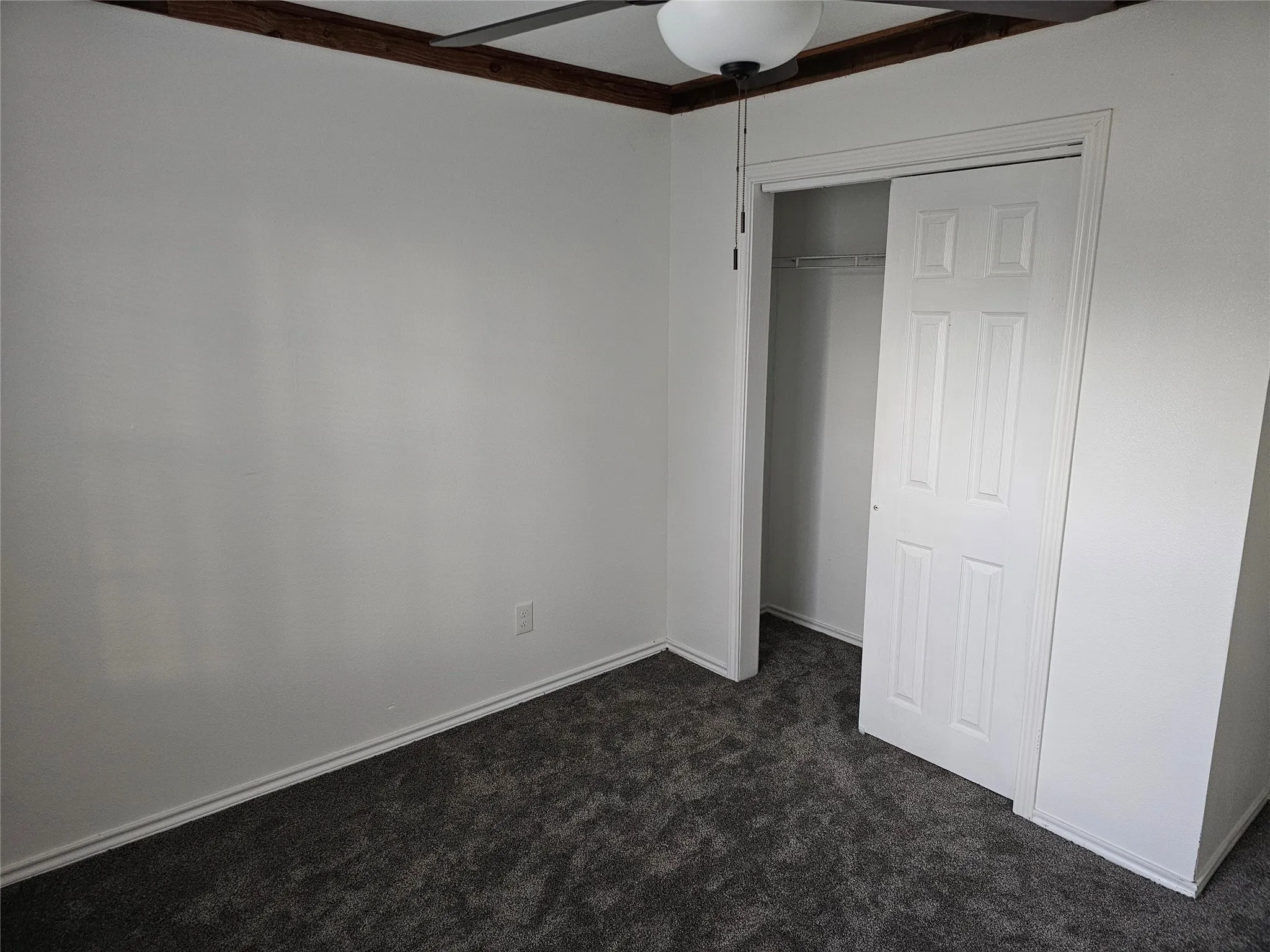 Unfurnished bedroom featuring dark colored carpet and a closet
