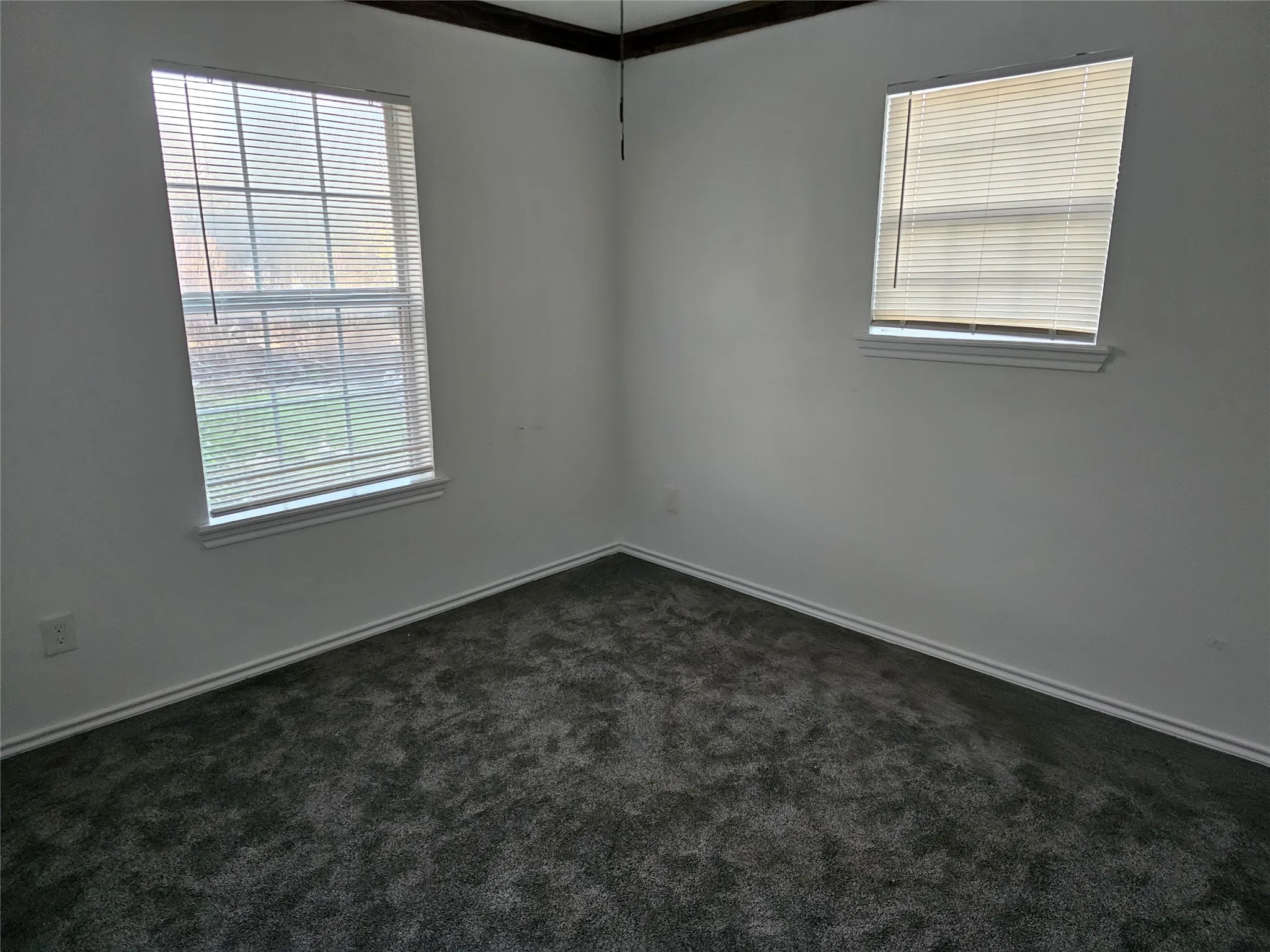 Unfurnished room with plenty of natural light and dark carpet