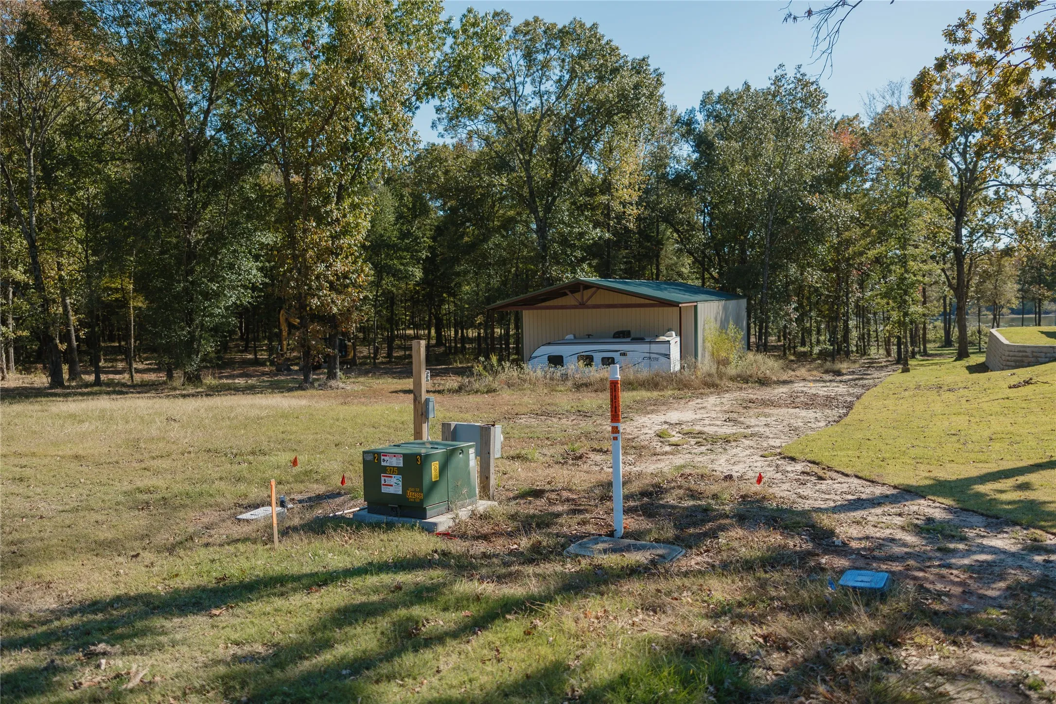 View of grassy yard with view of scattered trees and an outbuilding