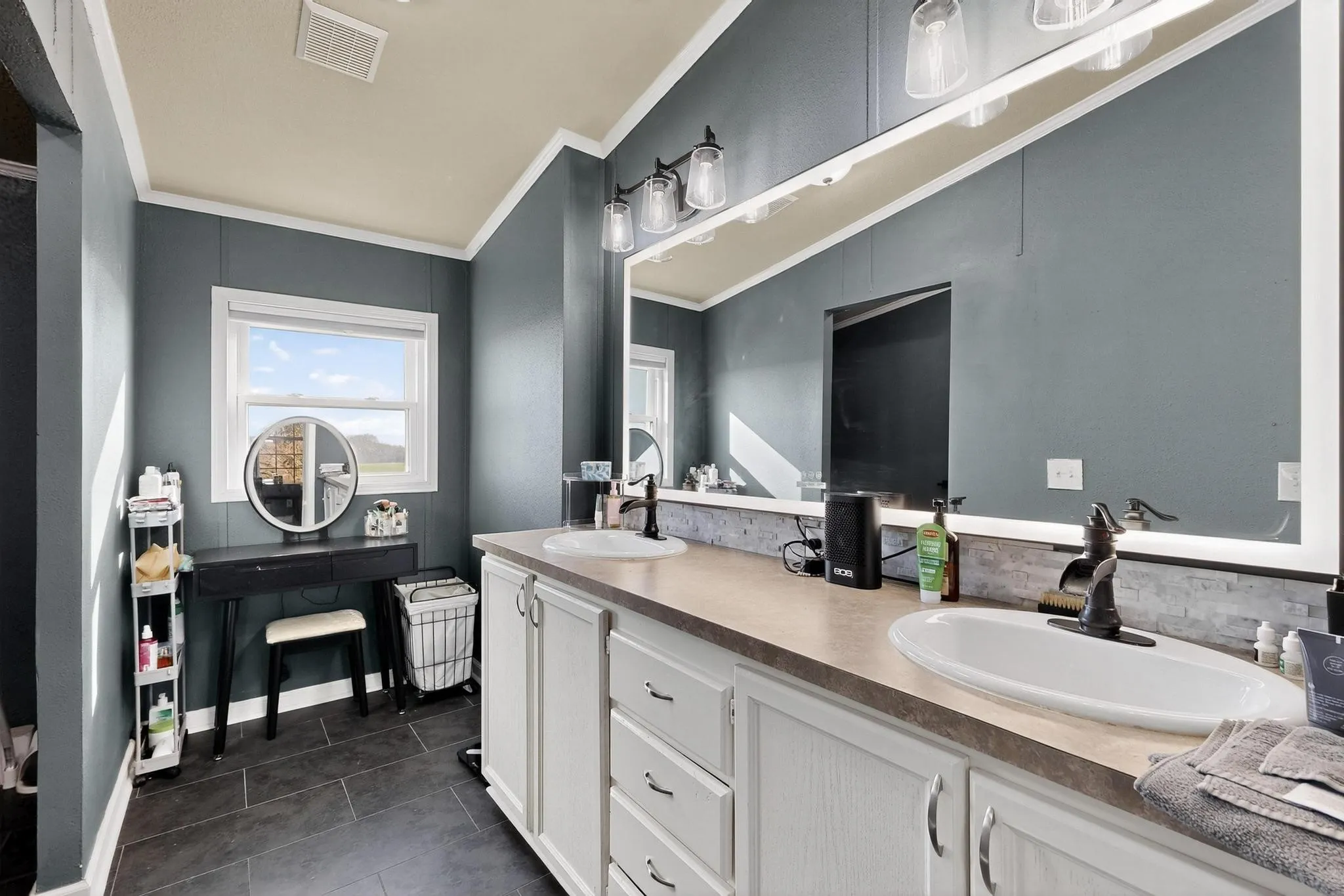 Full bathroom featuring double vanity, dark tile patterned floors, and ornamental molding