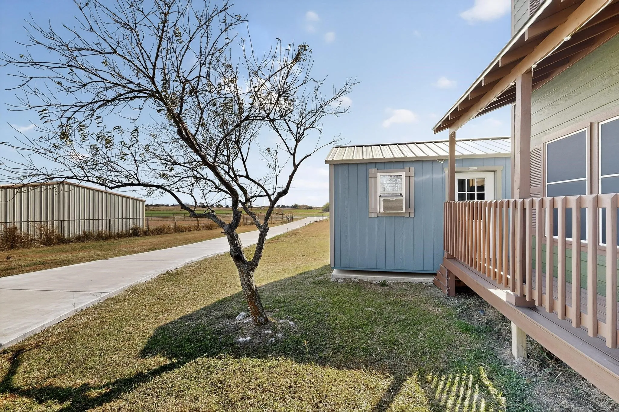 View of green lawn with an outdoor structure and a deck