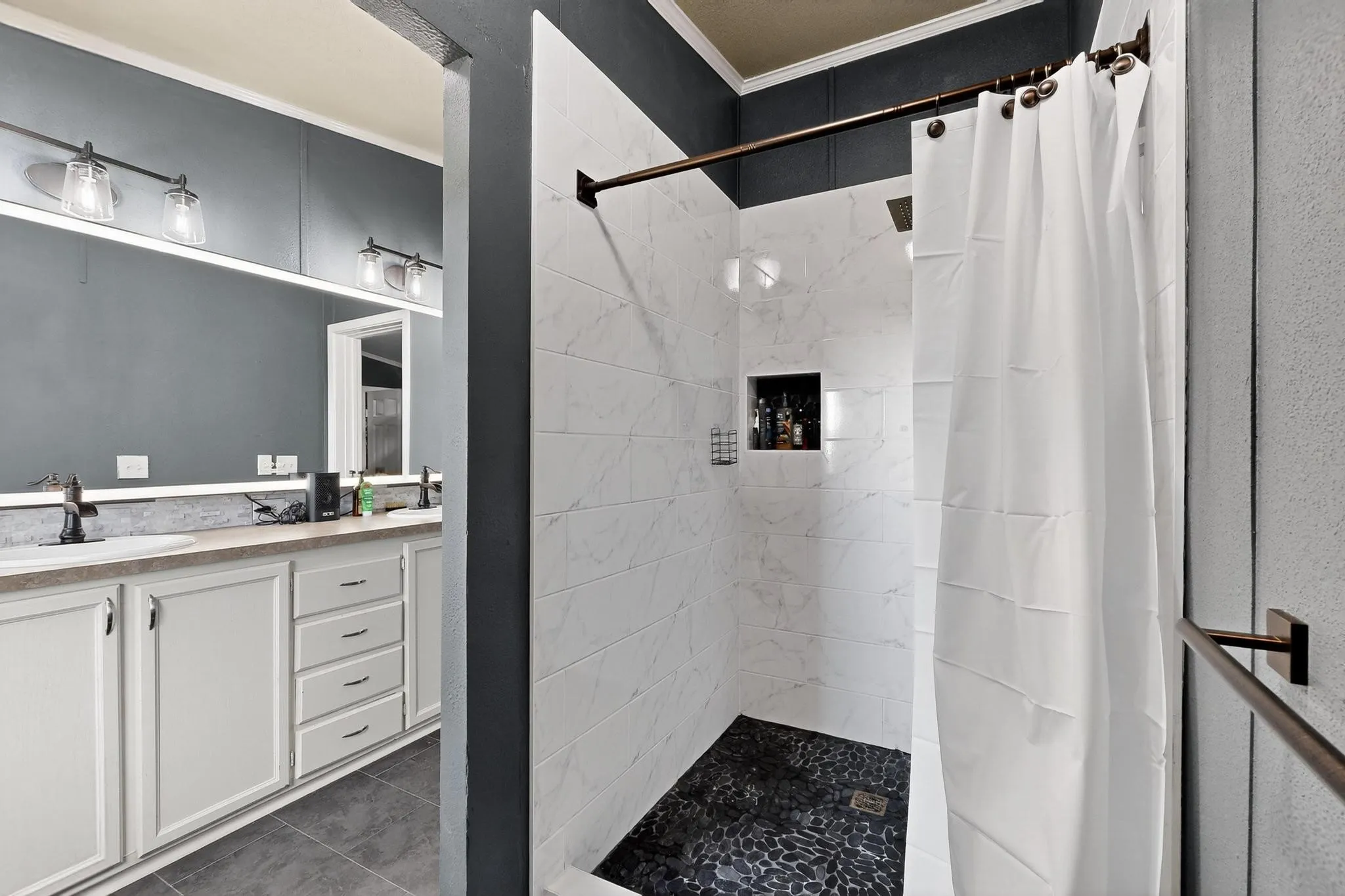 Bathroom featuring a stall shower, vanity, dark tile patterned flooring, and crown molding
