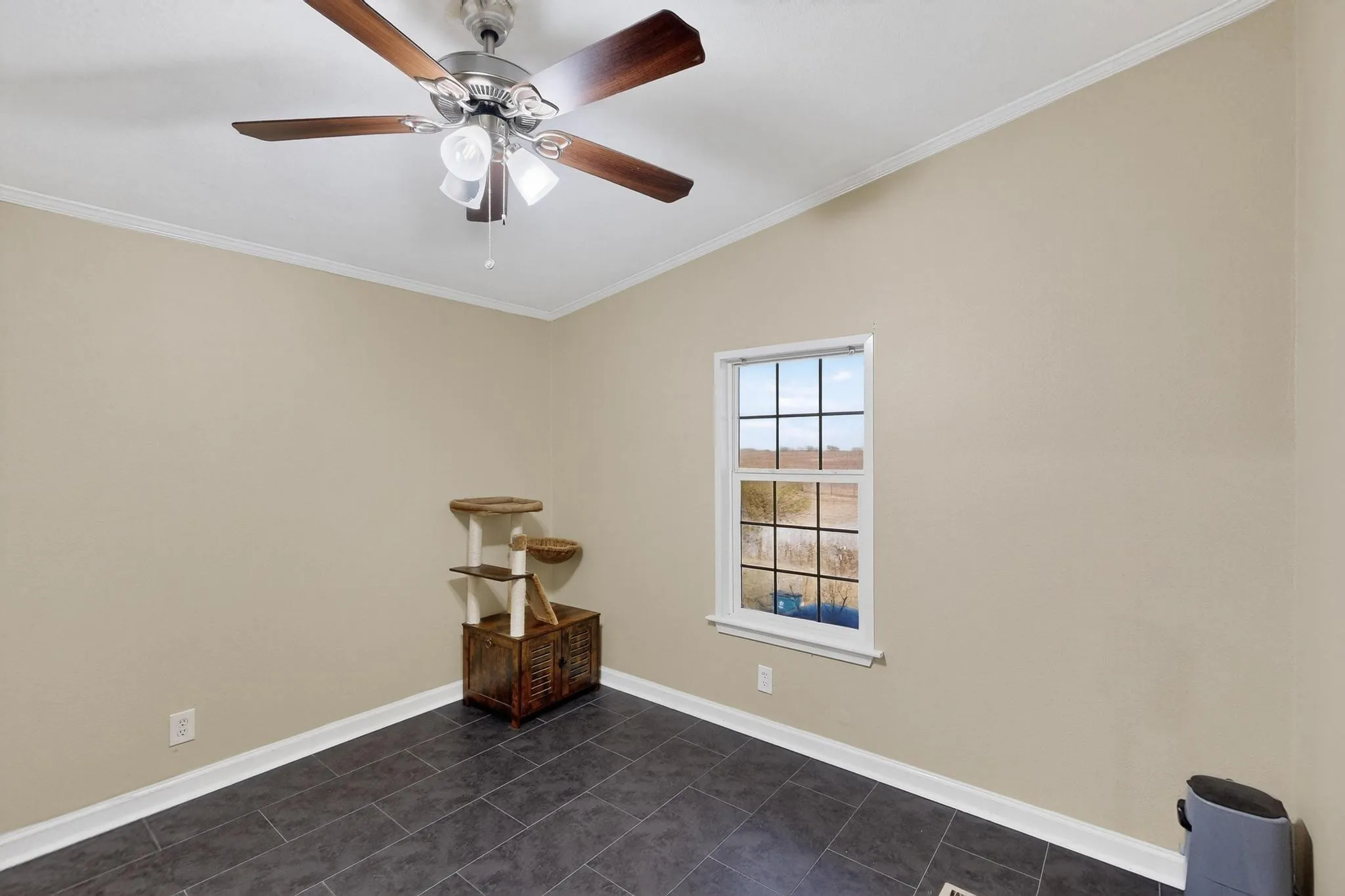 Spare room featuring crown molding, dark tile patterned floors, vaulted ceiling, and ceiling fan