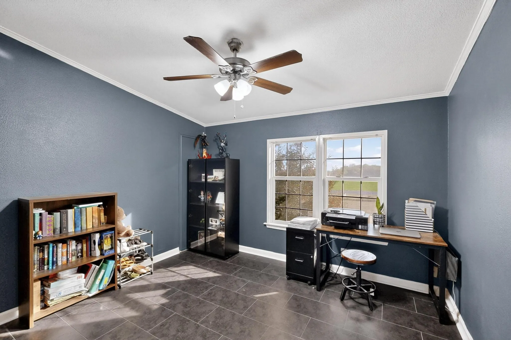 Office space featuring crown molding, dark tile patterned floors, a ceiling fan, and a textured wall