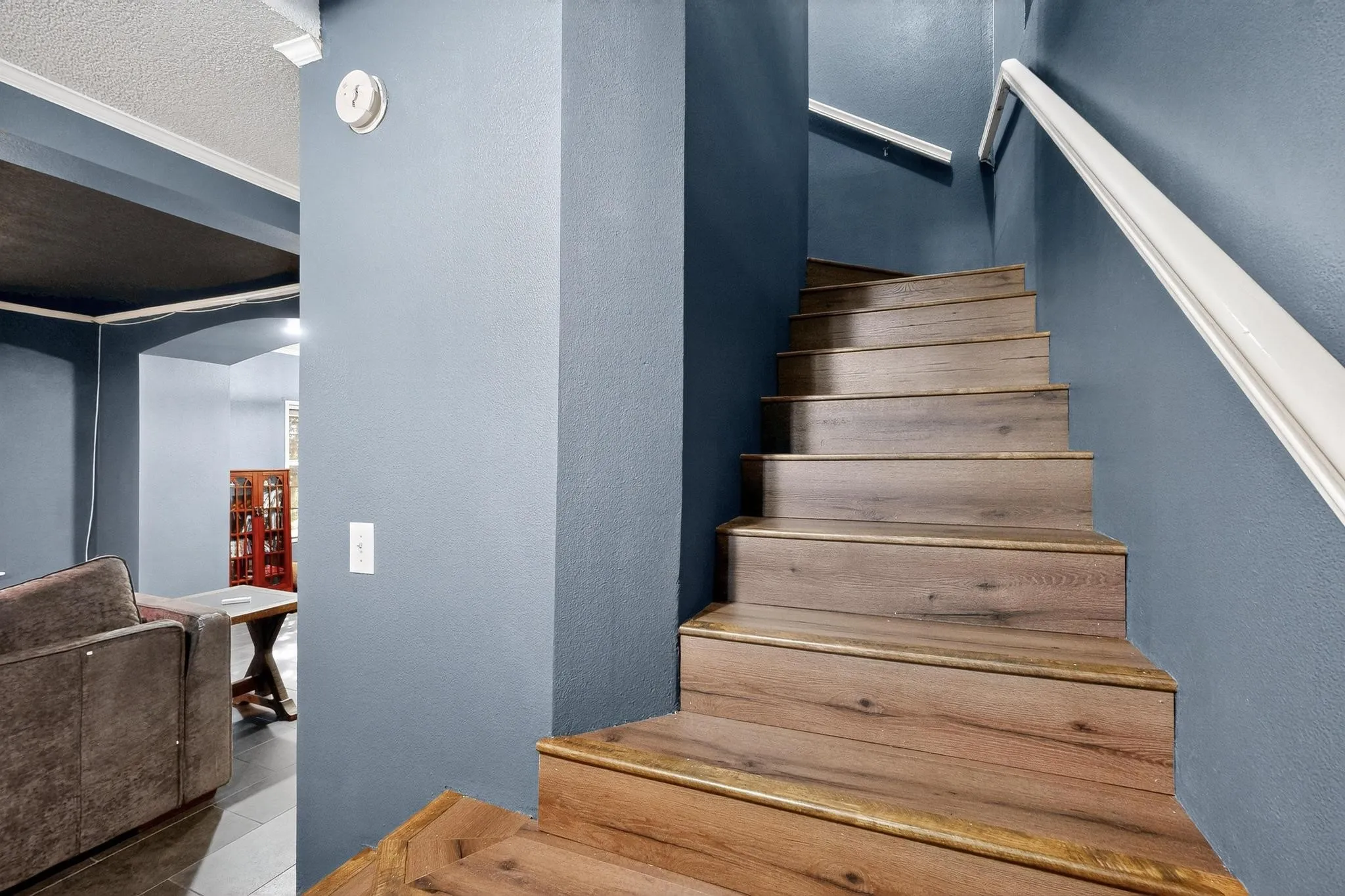 Stairway featuring arched walkways, a textured wall, a textured ceiling, and tile patterned floors