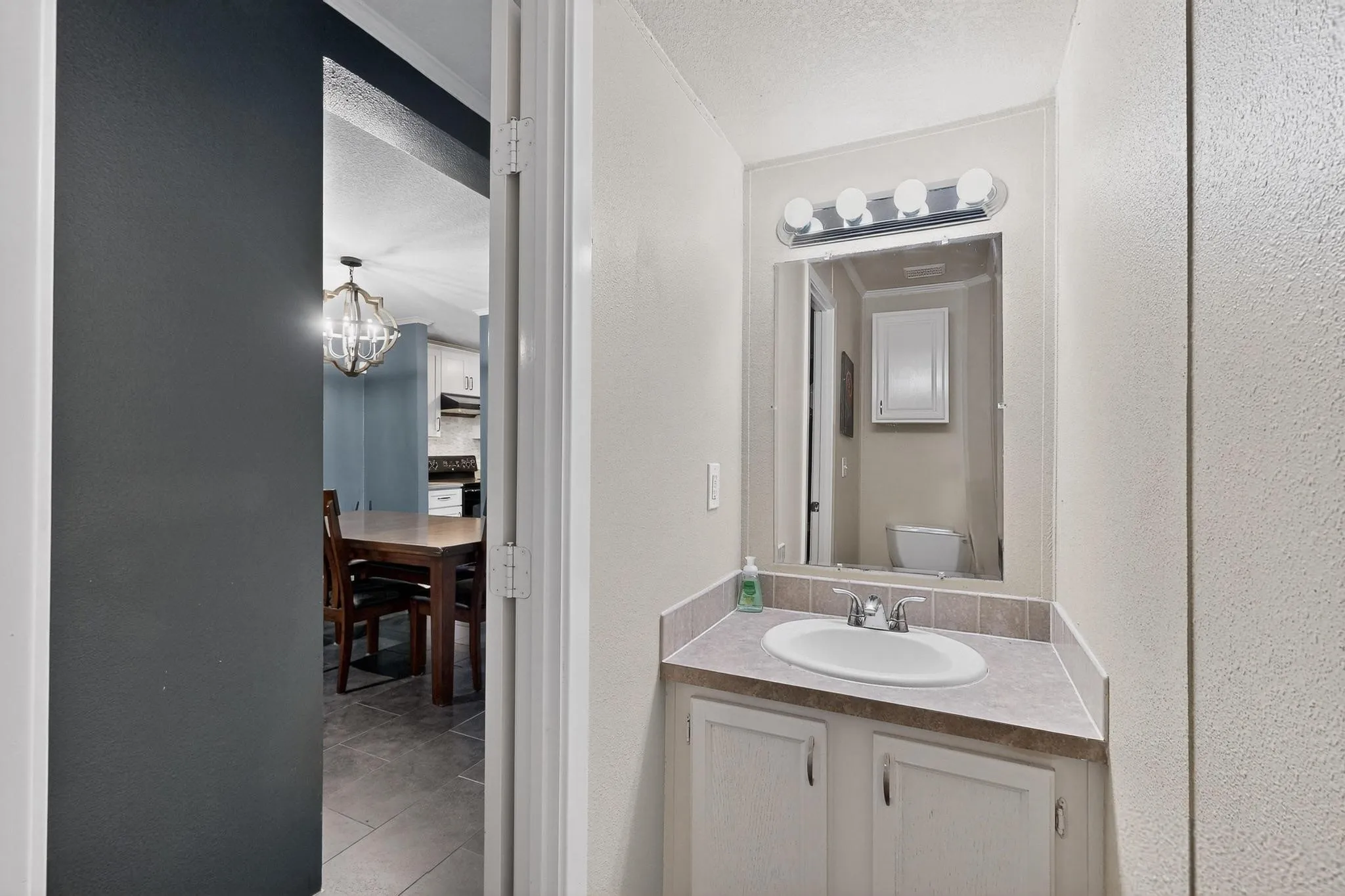 Half bath with light tile patterned flooring, a textured wall, a textured ceiling, vanity, and backsplash