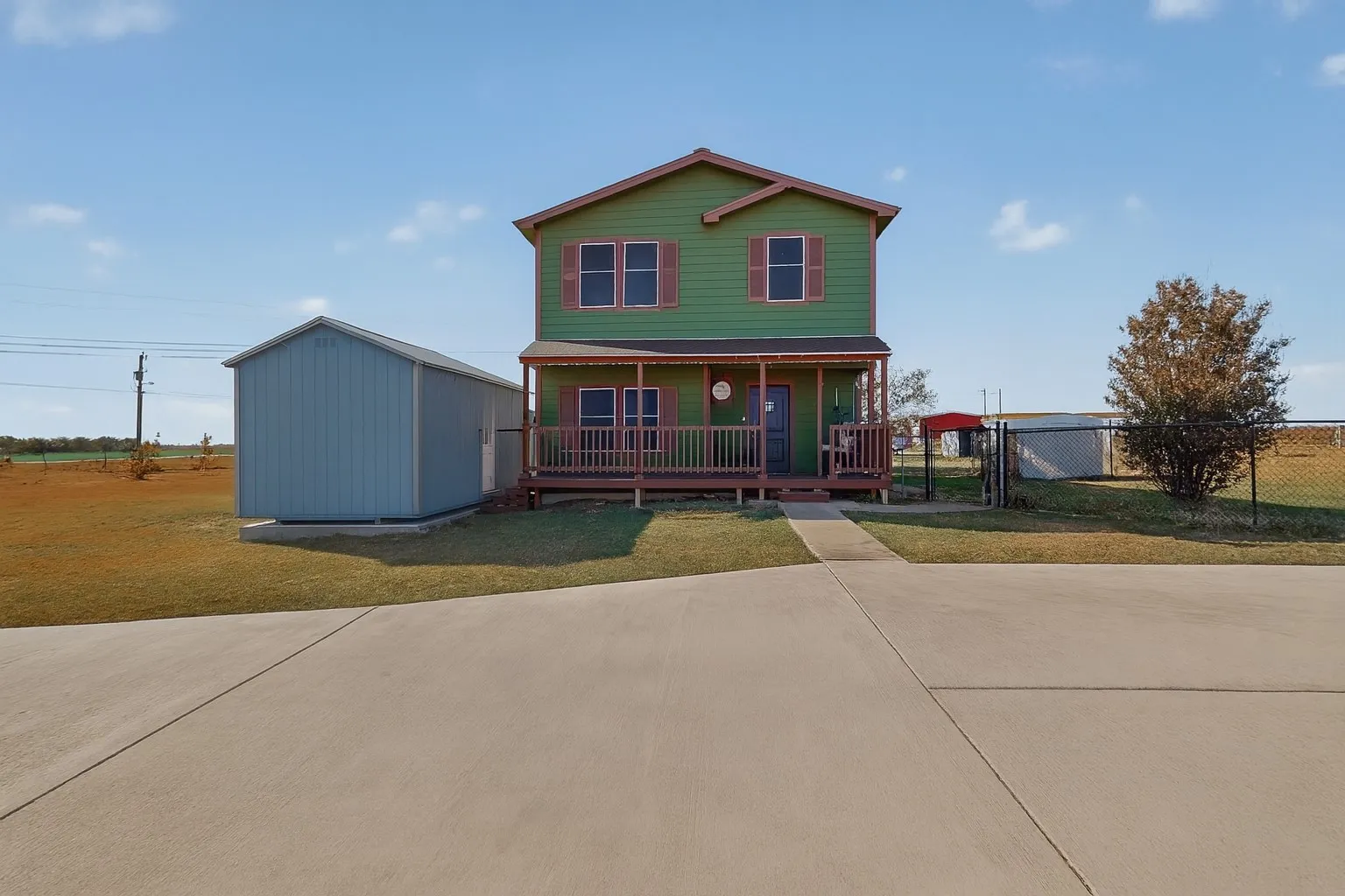 View of front of home featuring a porch, a storage unit, and a gate