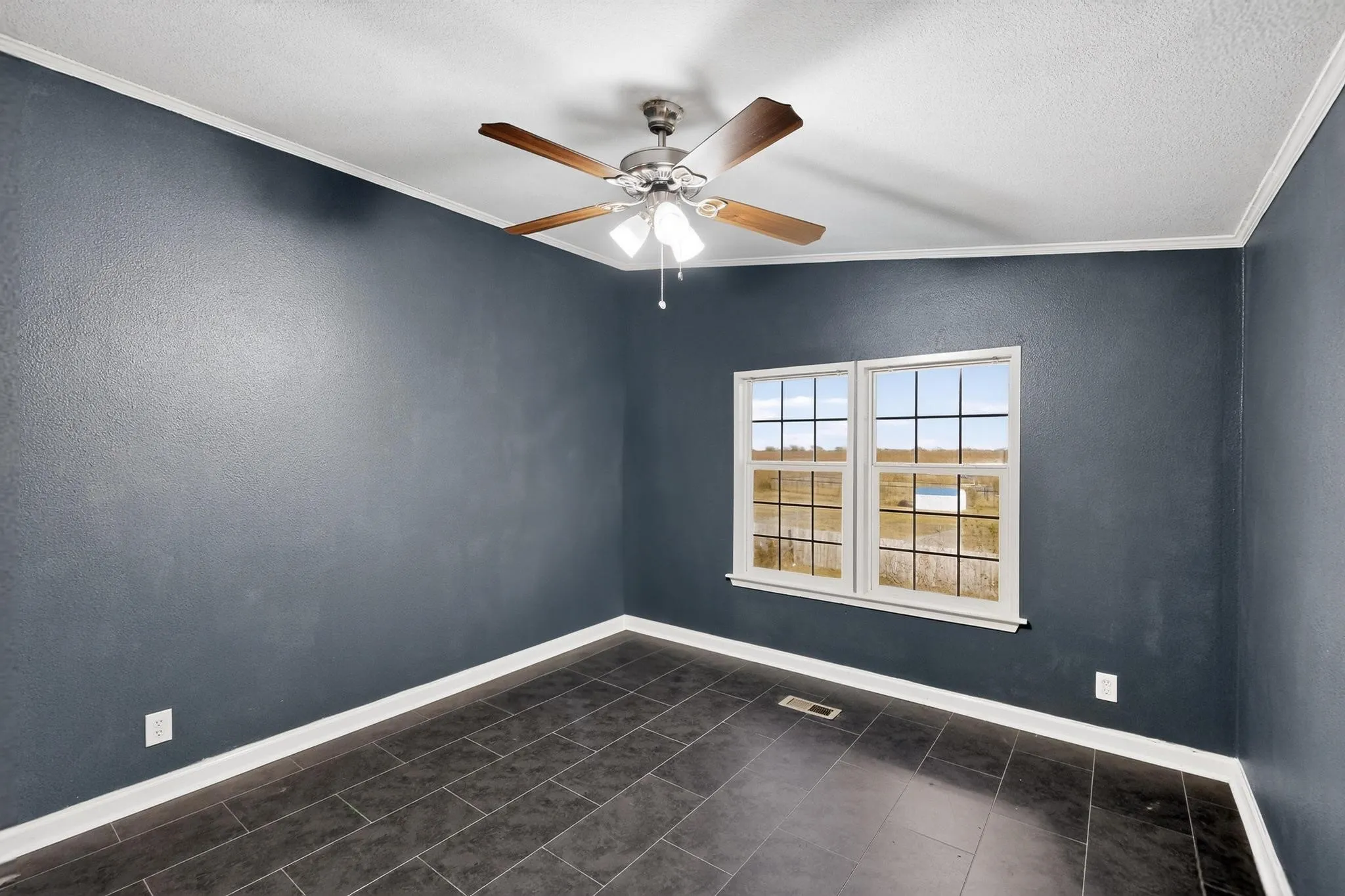 Unfurnished room with crown molding, a ceiling fan, a textured ceiling, dark tile patterned floors, and a textured wall