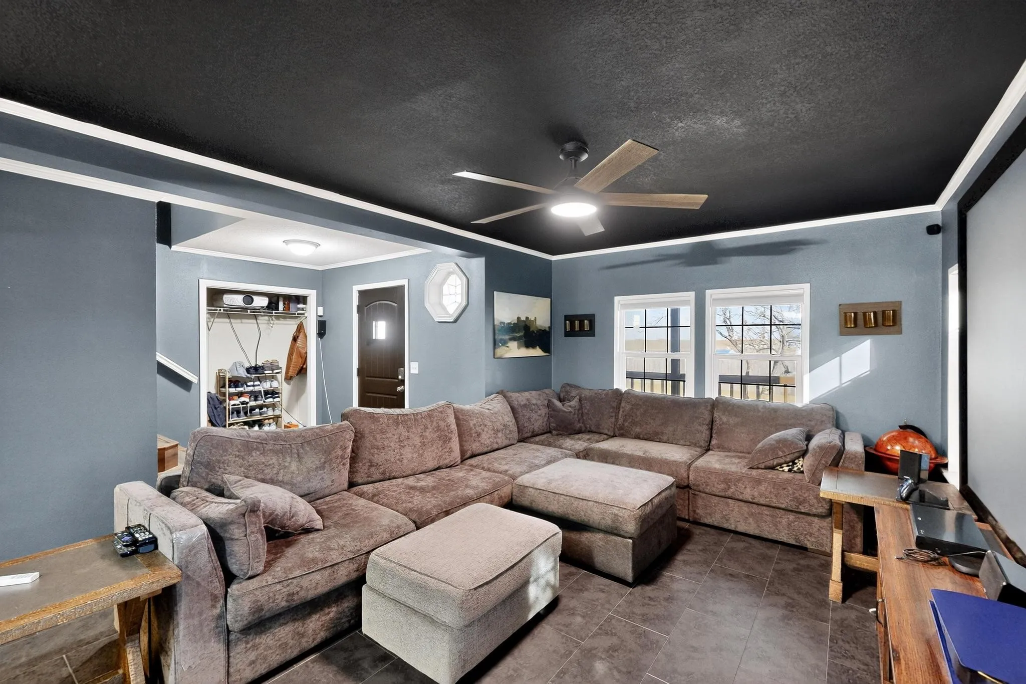 Living area with crown molding, a textured ceiling, ceiling fan, and tile patterned floors