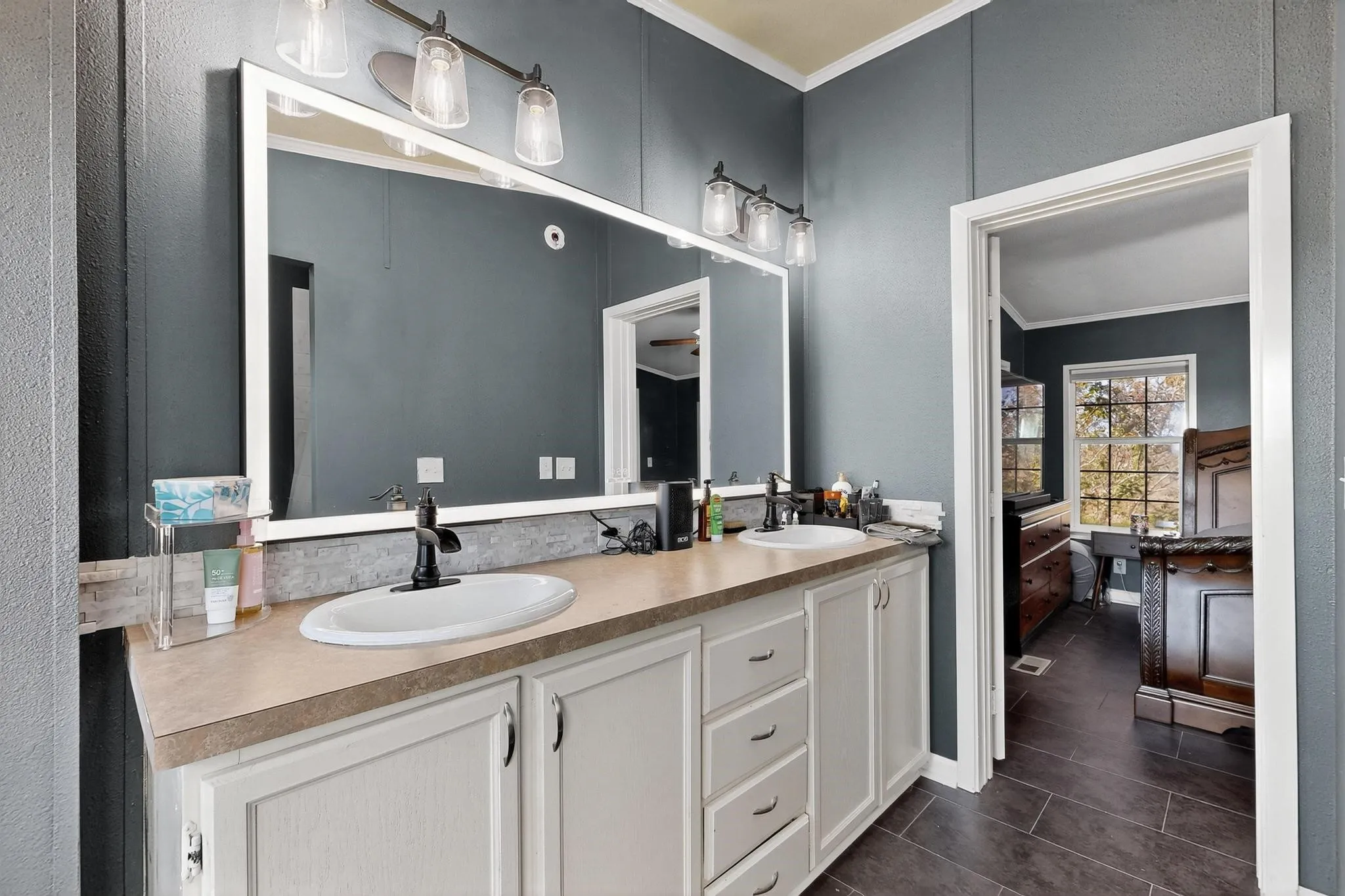 Full bath featuring ornamental molding, double vanity, and dark tile patterned floors