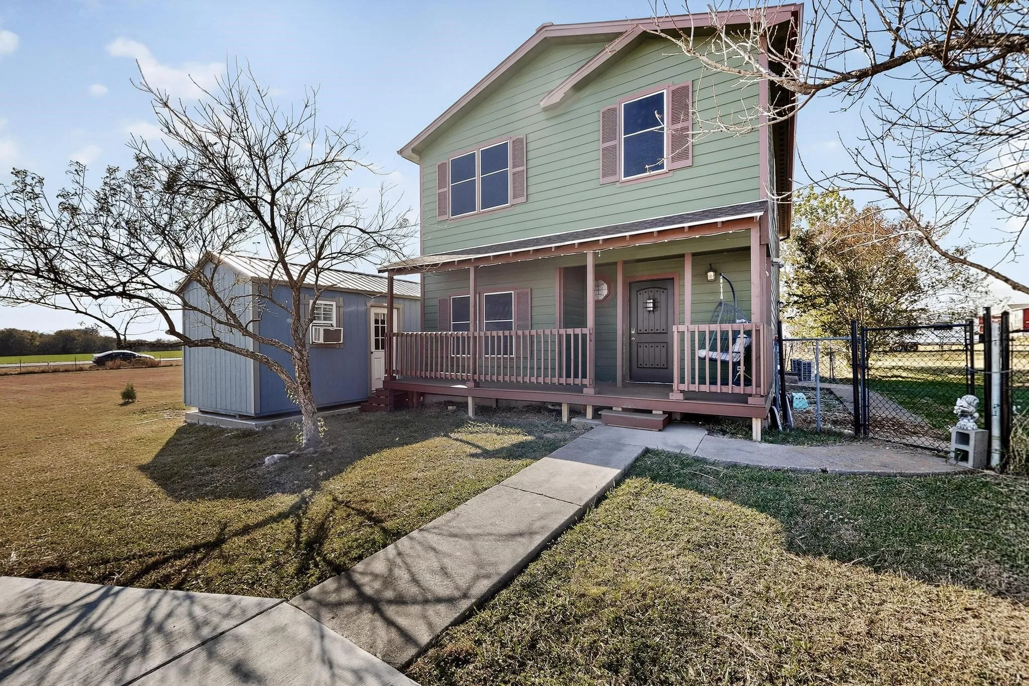 Traditional-style home featuring a gate, a shed, and a porch