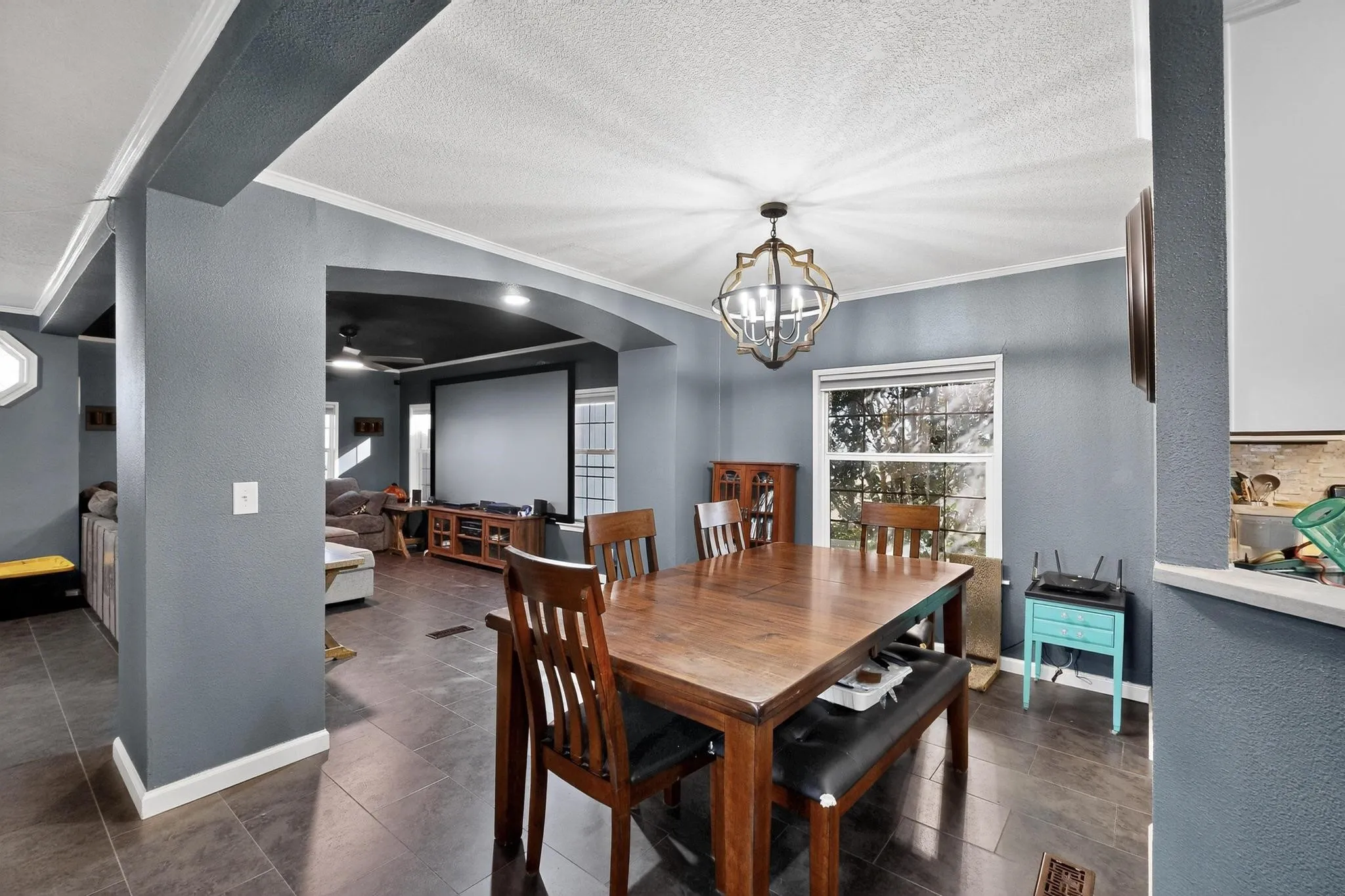 Dining room featuring a textured wall, arched walkways, crown molding, a textured ceiling, and a chandelier