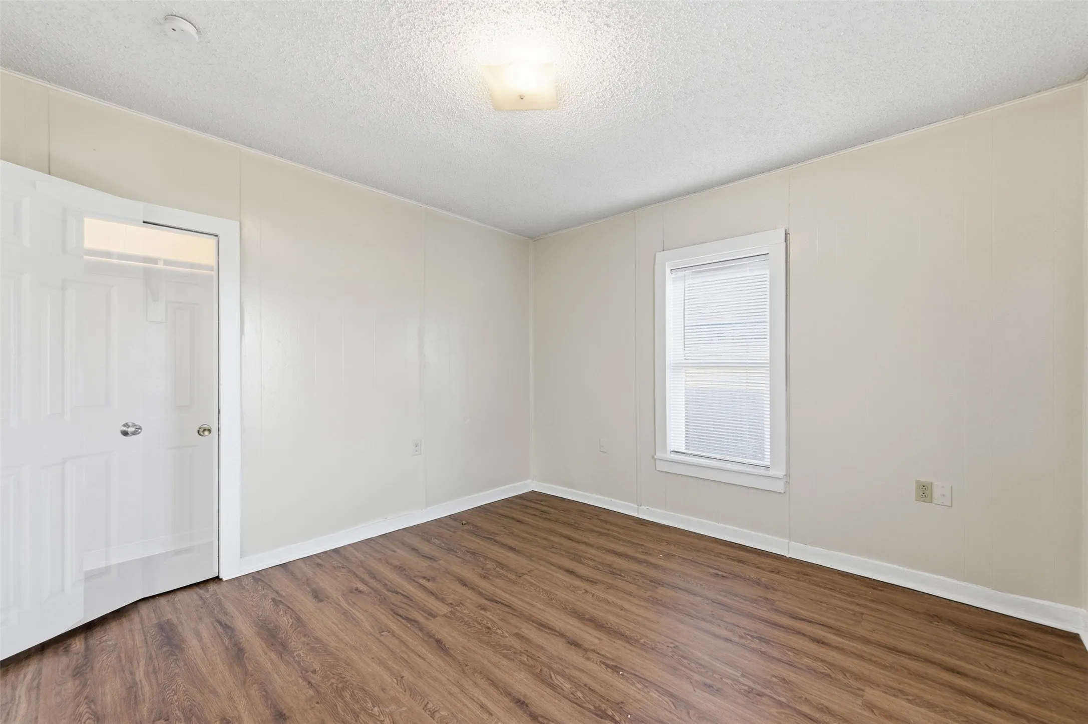 Unfurnished bedroom with a textured ceiling and dark wood-style floors