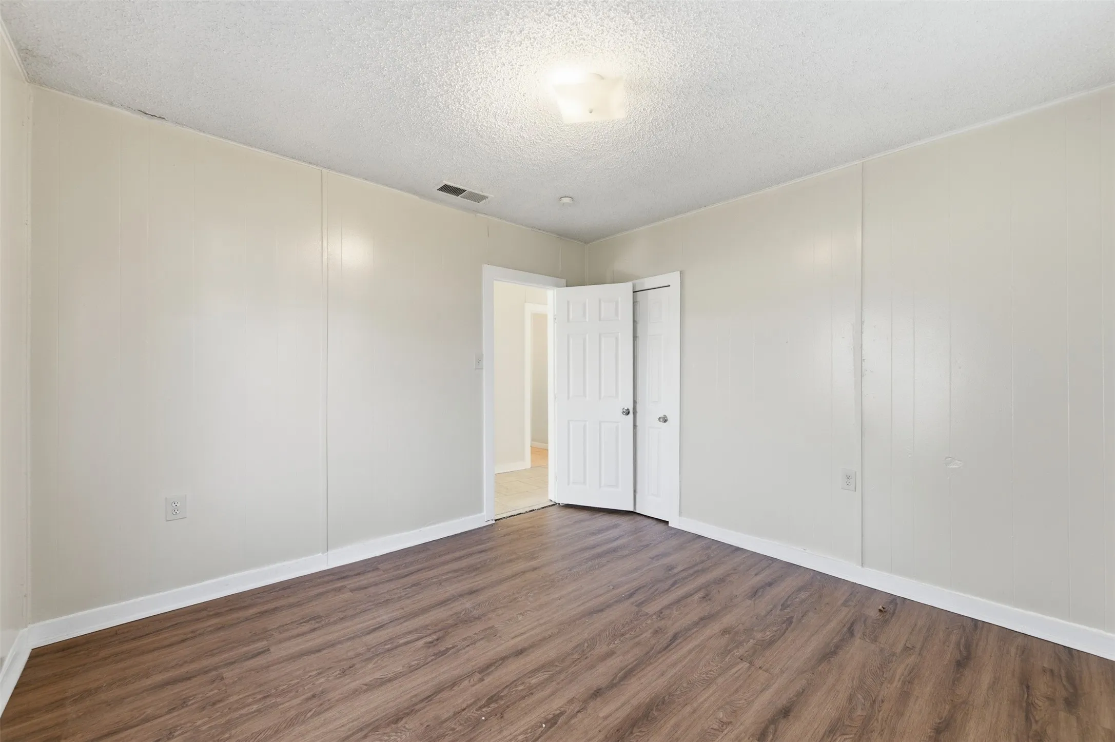 Unfurnished bedroom with dark wood-type flooring and a textured ceiling