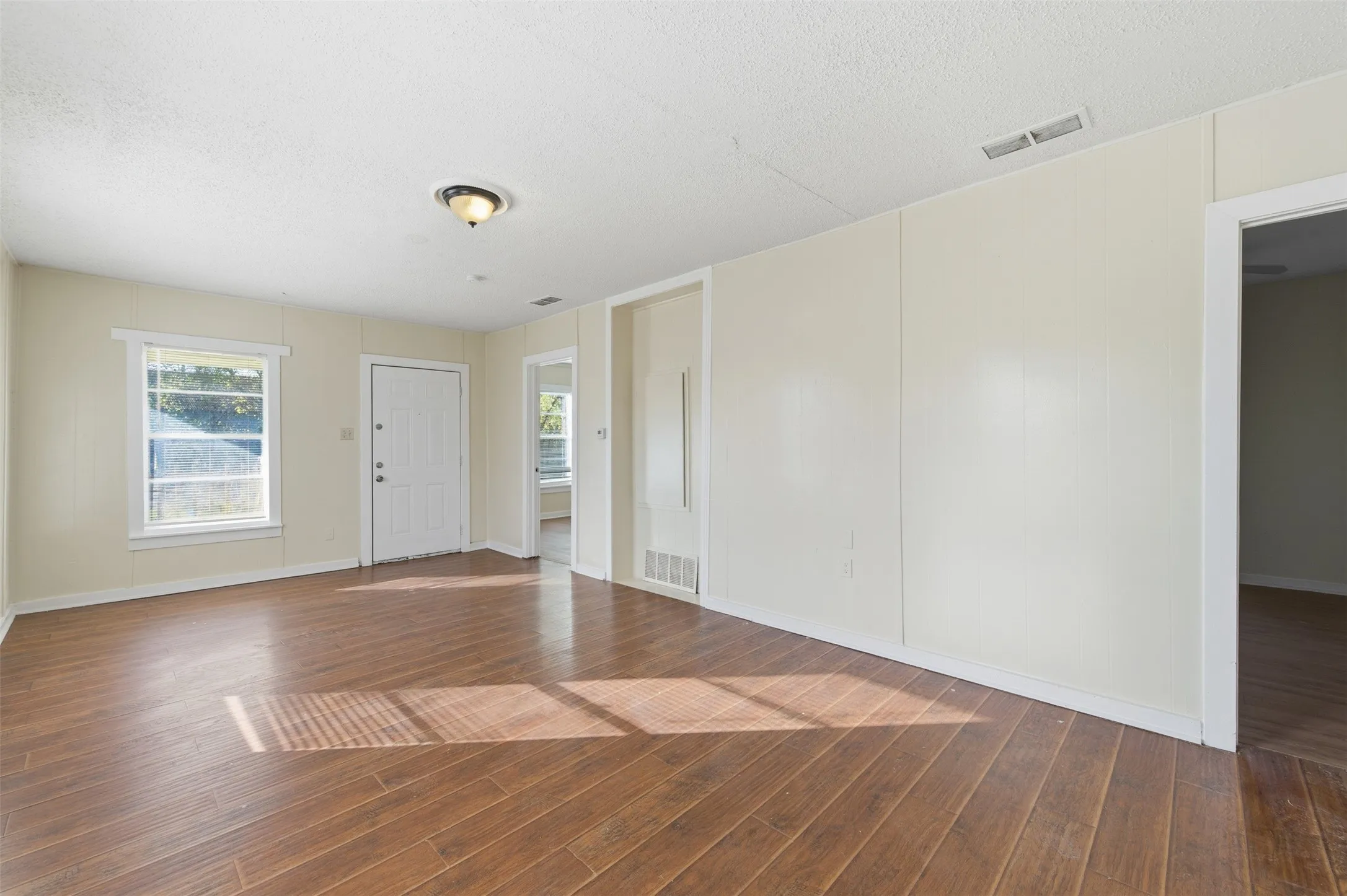 Empty room with a textured ceiling and wood finished floors