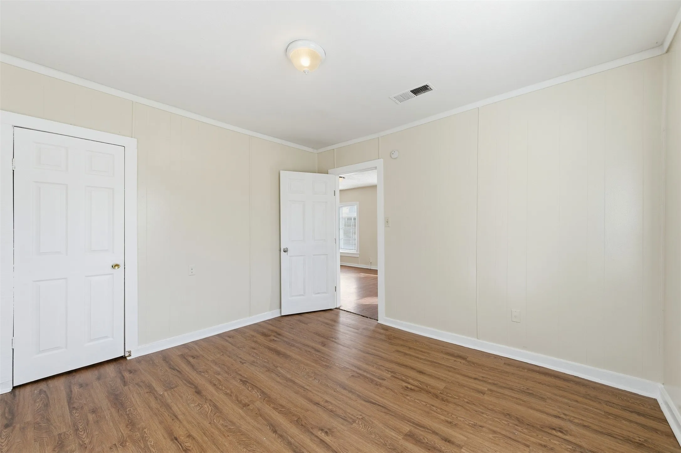 Unfurnished bedroom featuring crown molding and wood finished floors