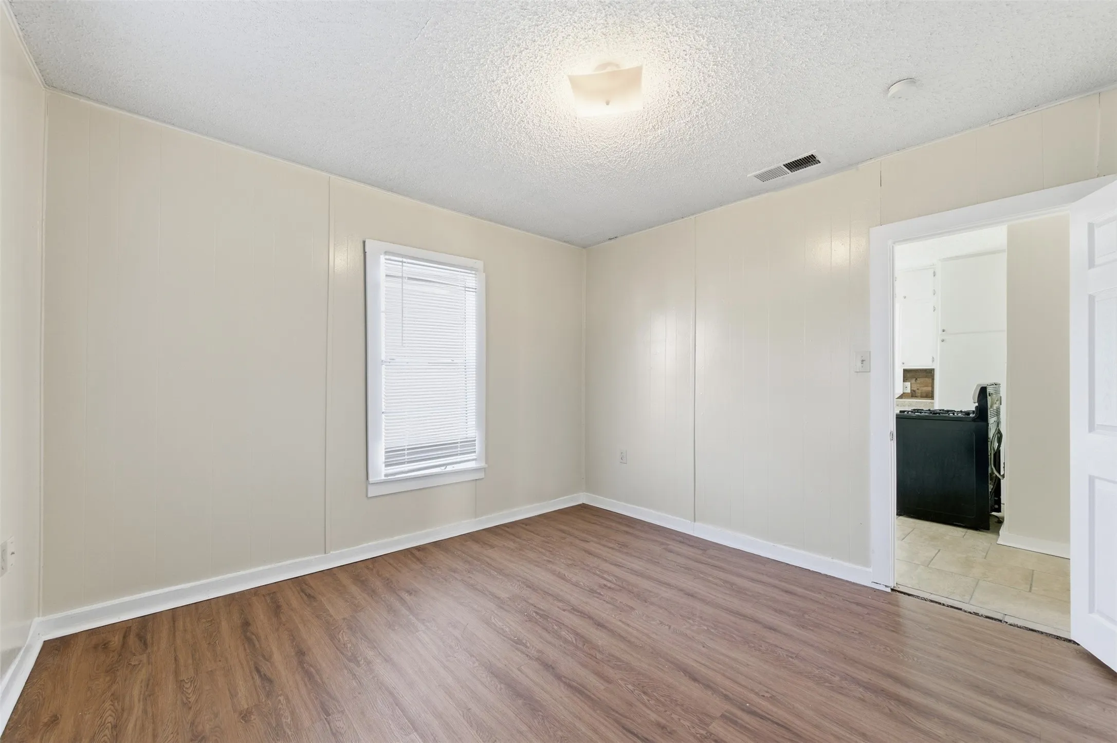 Empty room featuring wood finished floors and a textured ceiling