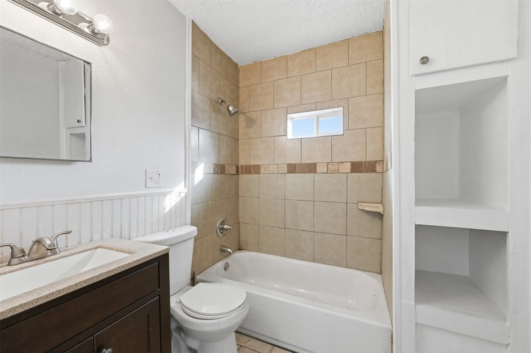 Bathroom featuring shower / washtub combination, vanity, a textured ceiling, and a wainscoted wall