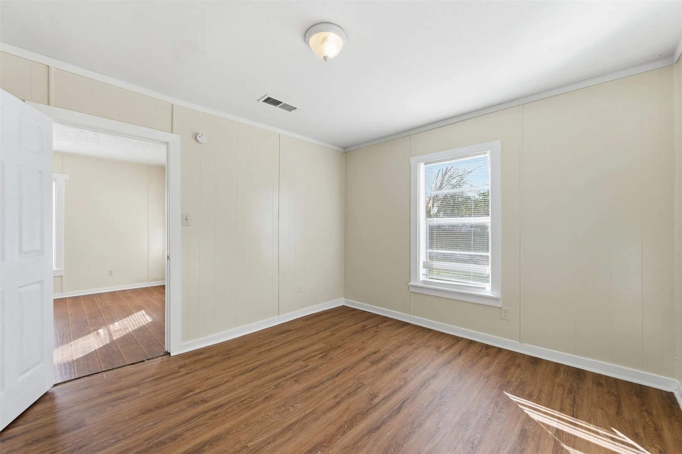 Spare room with wood finished floors and crown molding