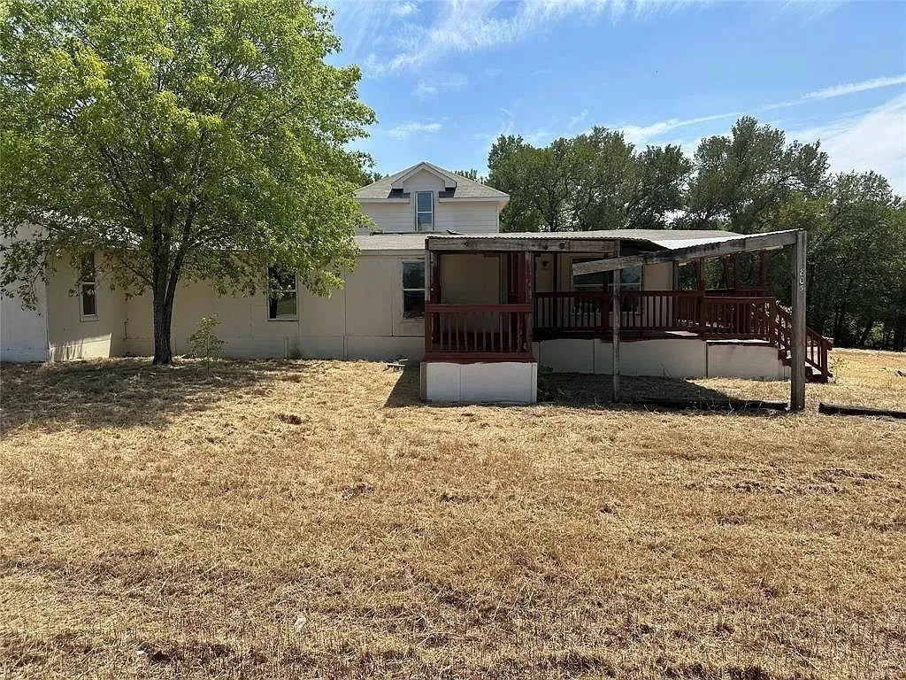 Rear view of house featuring a porch and a yard