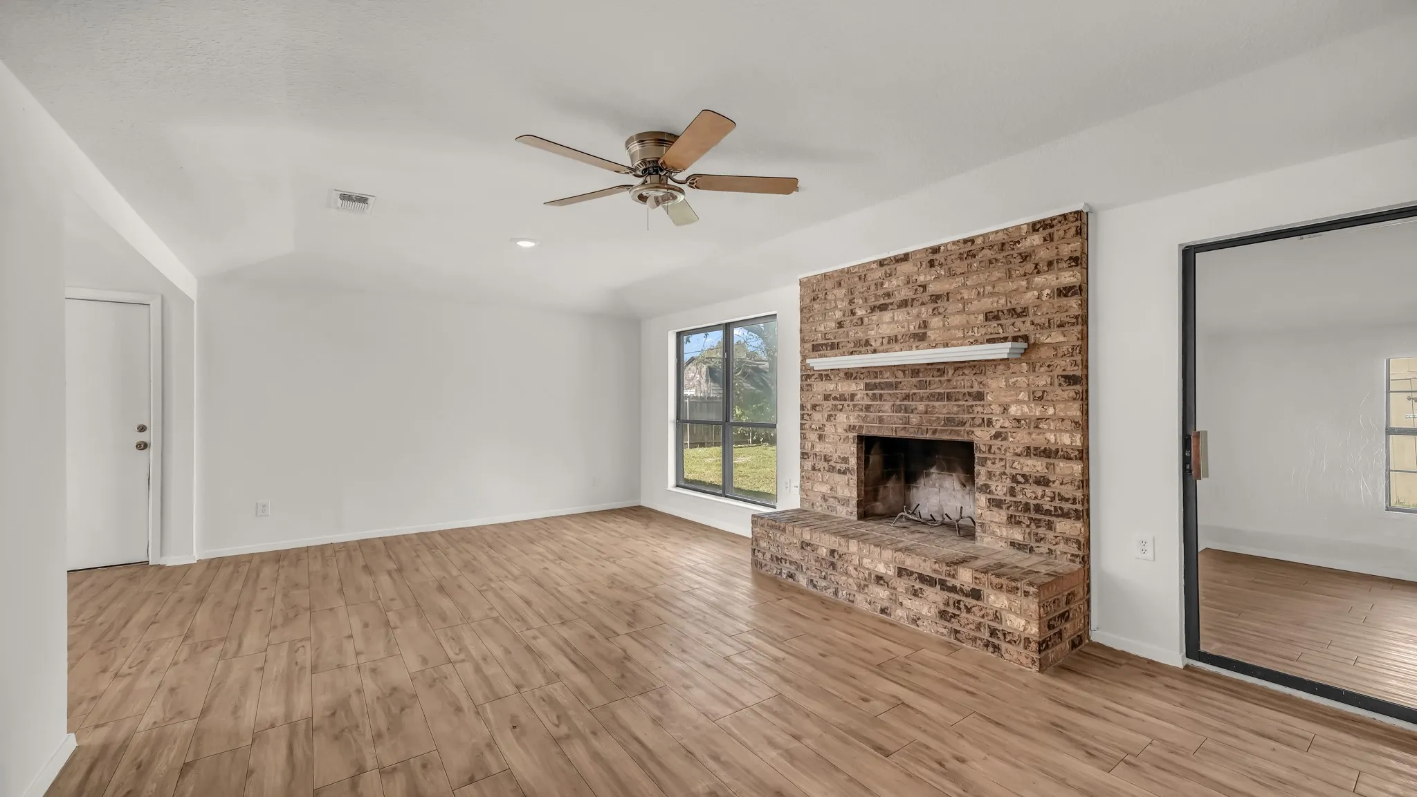 Unfurnished living room with light wood finished floors, a fireplace, a ceiling fan, and recessed lighting