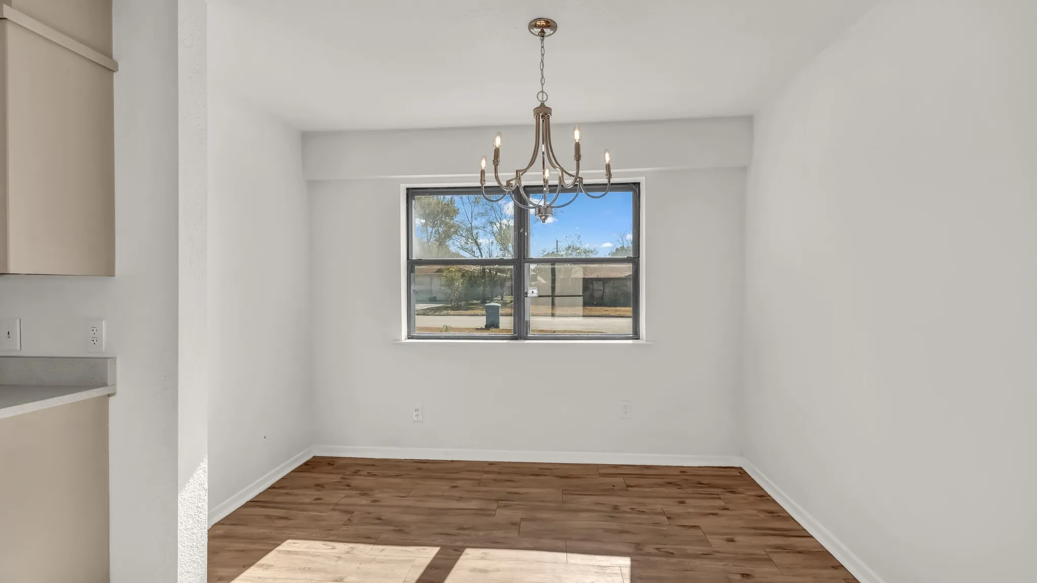 Unfurnished dining area featuring wood finished floors and a chandelier
