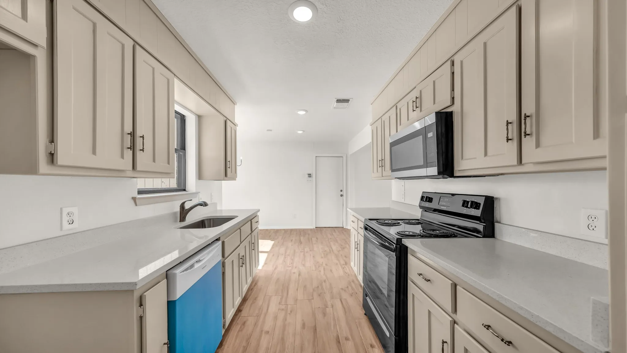 Kitchen featuring black range with electric cooktop, recessed lighting, light wood finished floors, stainless steel microwave, and dishwasher
