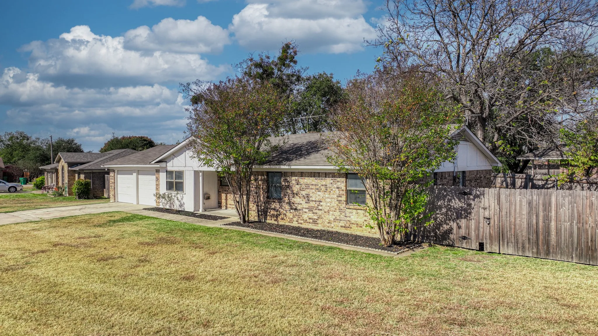 Ranch-style home with brick siding, roof with shingles, driveway, and an attached garage