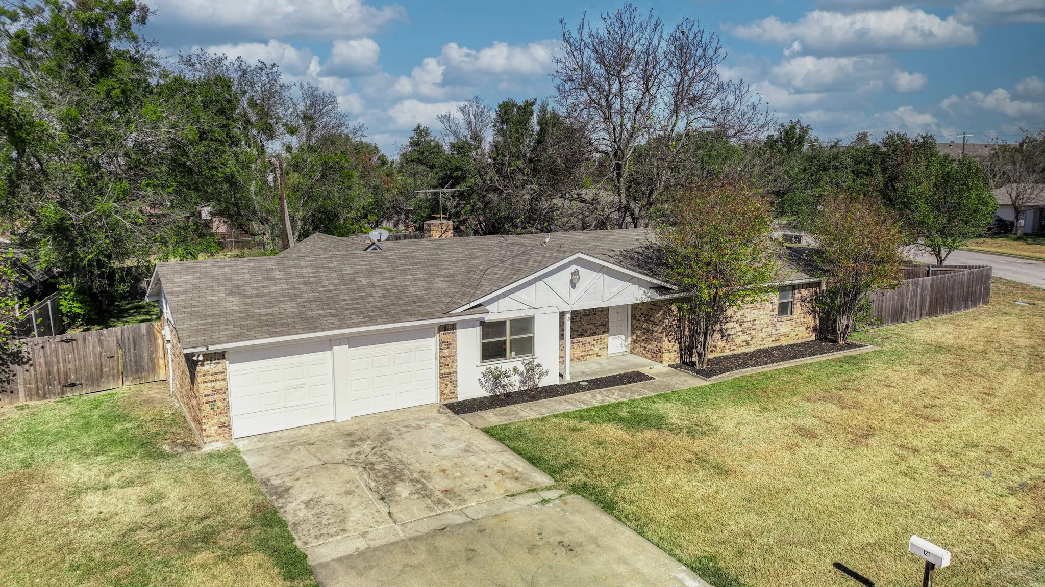 Ranch-style home with driveway, a shingled roof, a garage, and brick siding