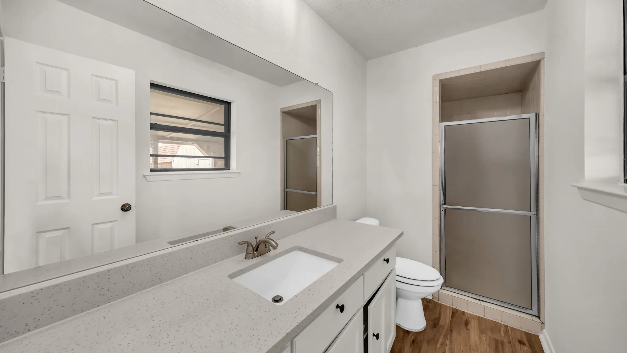 Full bath featuring dark wood-style floors, a stall shower, and vanity