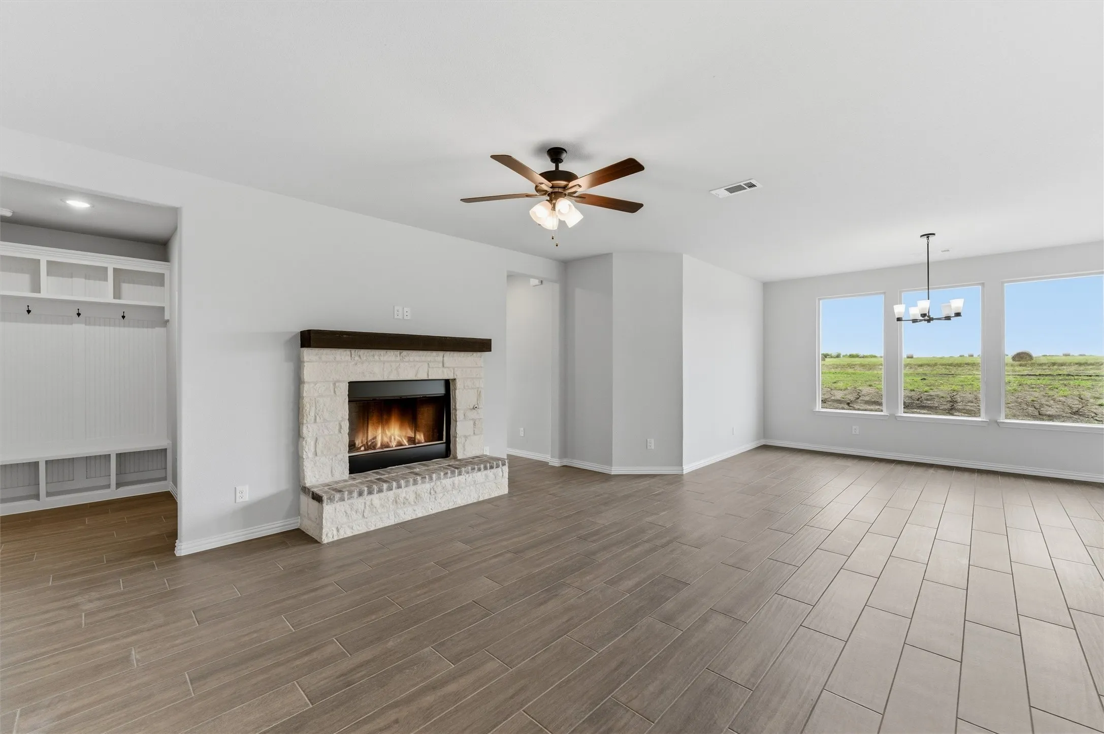 Unfurnished living room with a fireplace, ceiling fan, wood finish floors, and suspended lighting