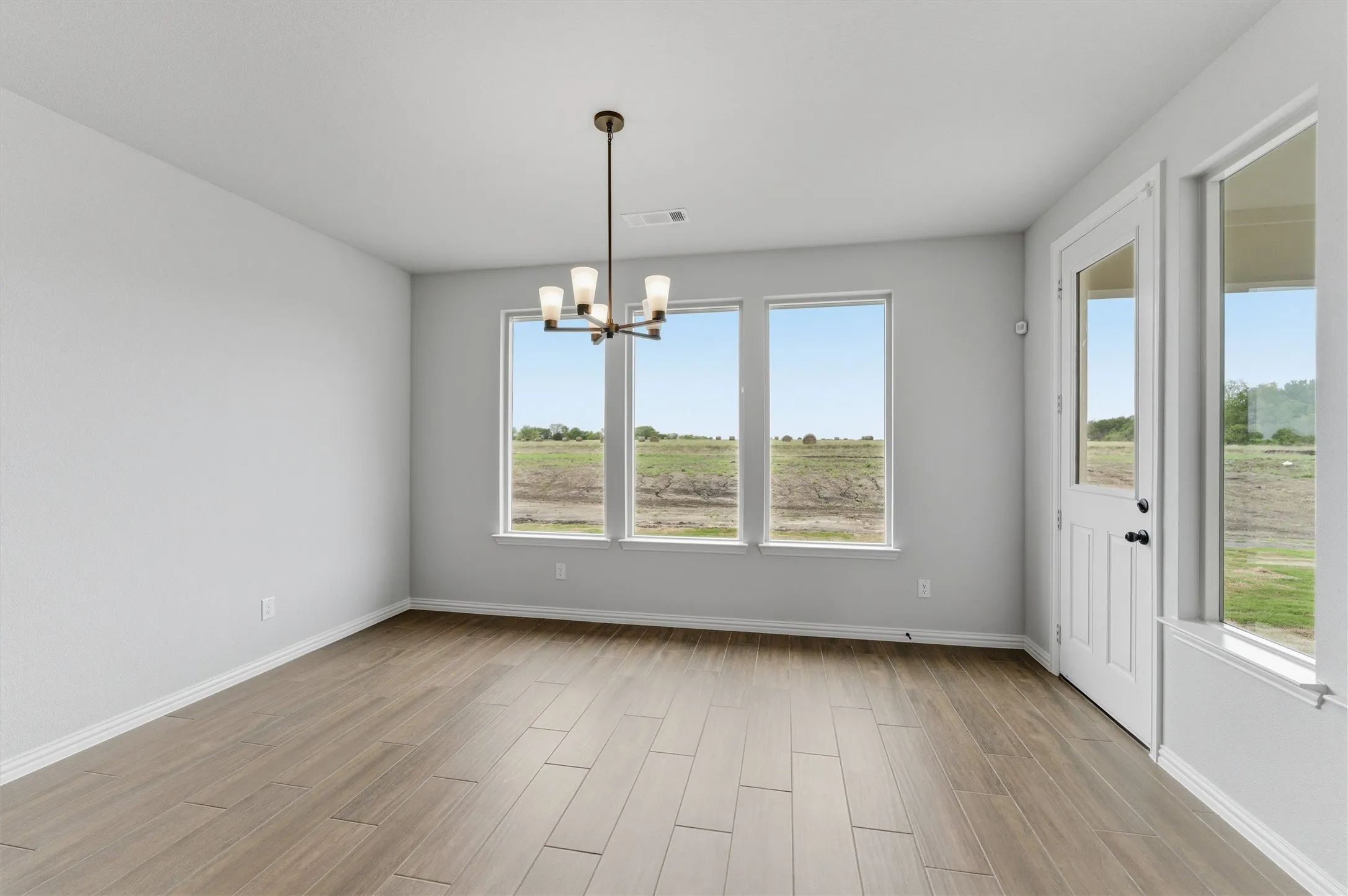 Unfurnished dining area featuring a chandelier and wood tiled floors
