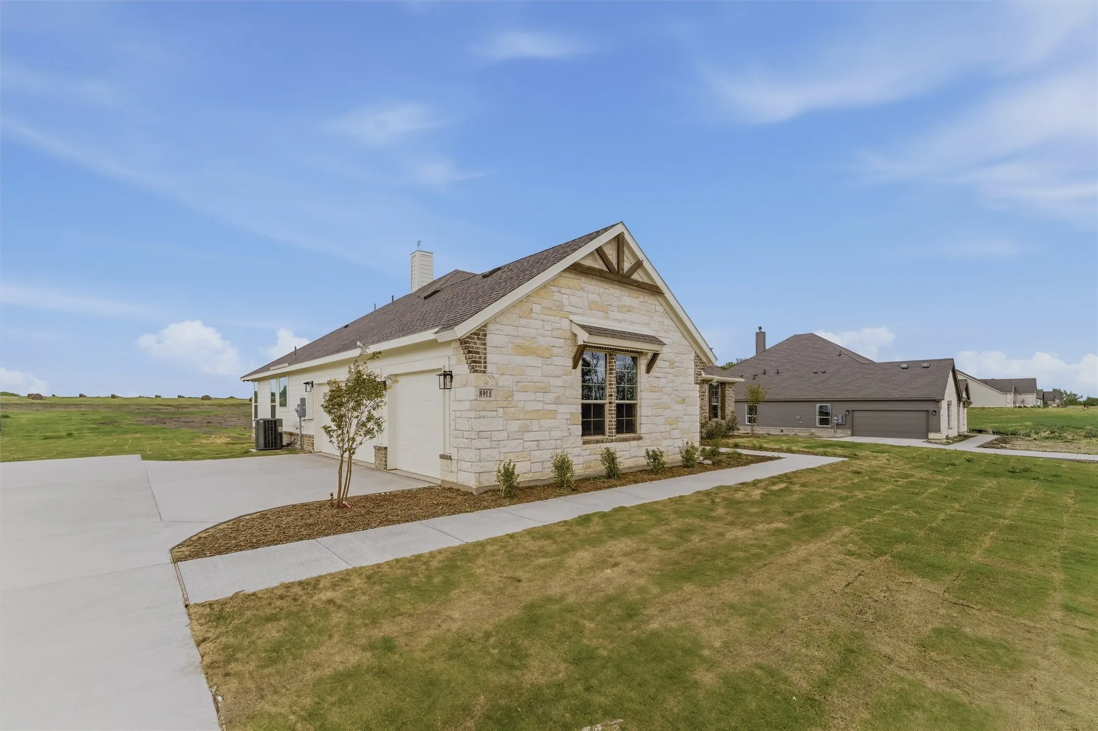 View of front of home with stone siding, a chimney, a front lawn, an attached garage, and concrete driveway