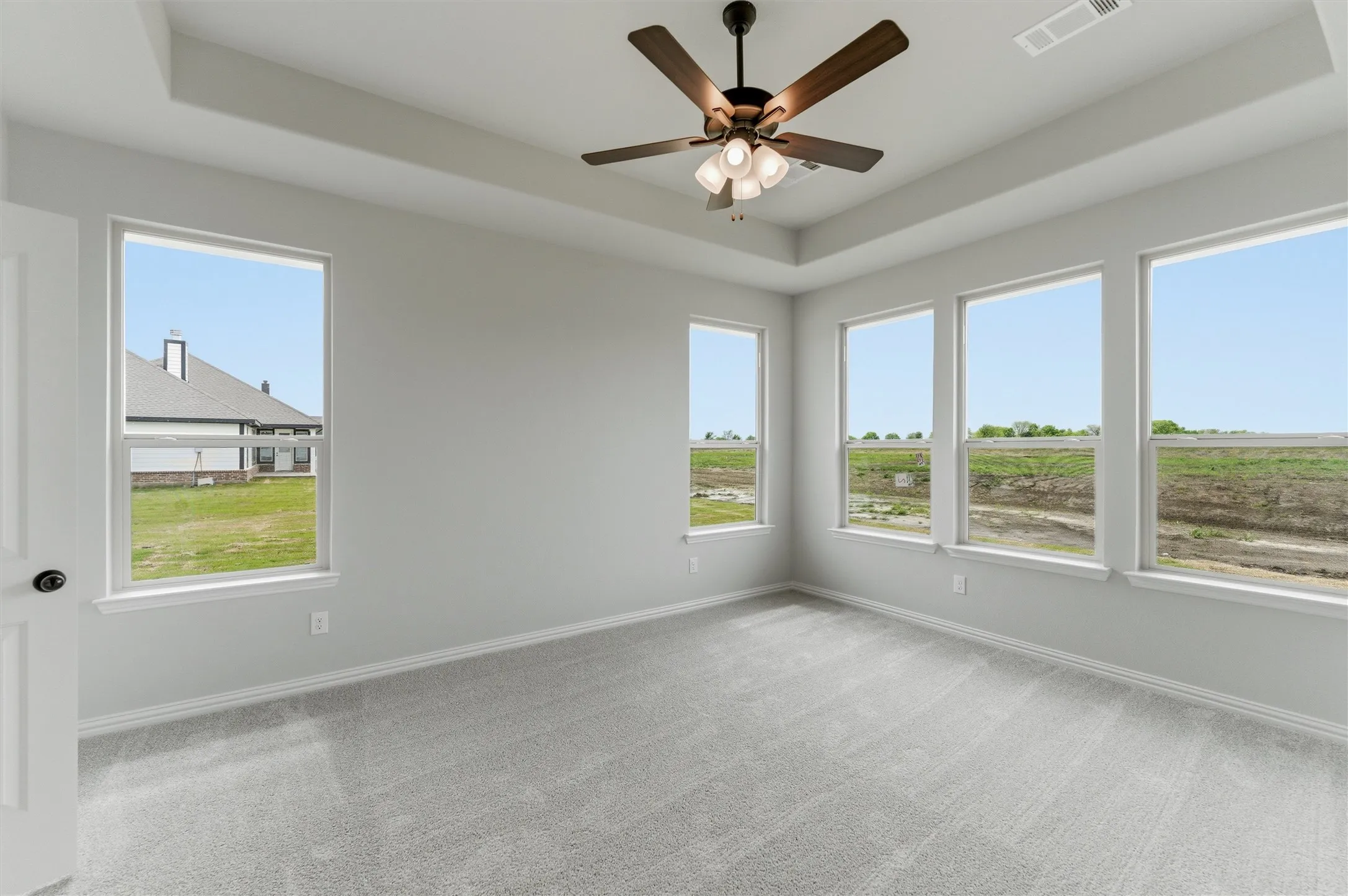 Spare room with a raised ceiling, a ceiling fan, and light colored carpet