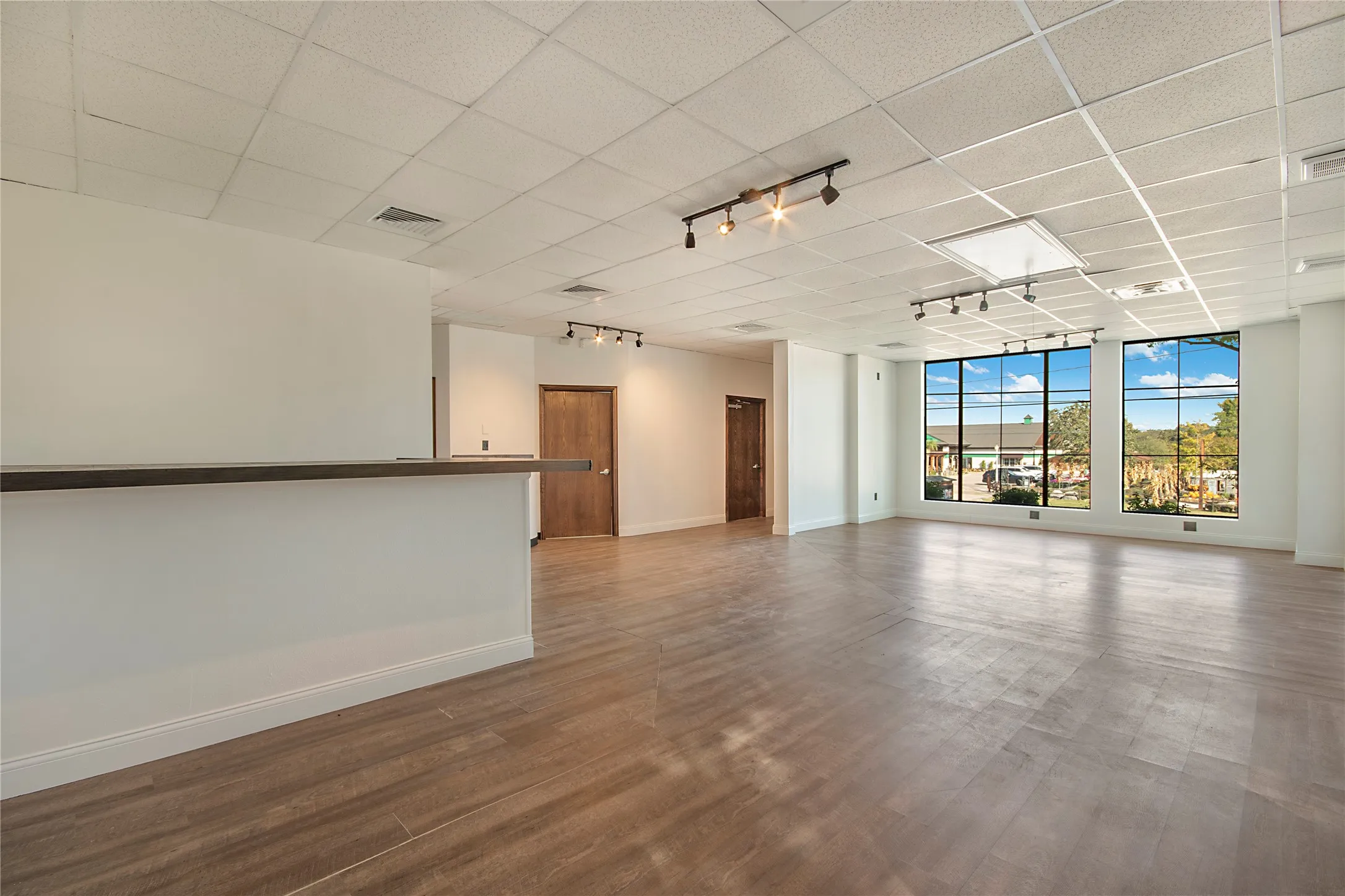 Empty room featuring rail lighting, a drop ceiling, and wood finished floors