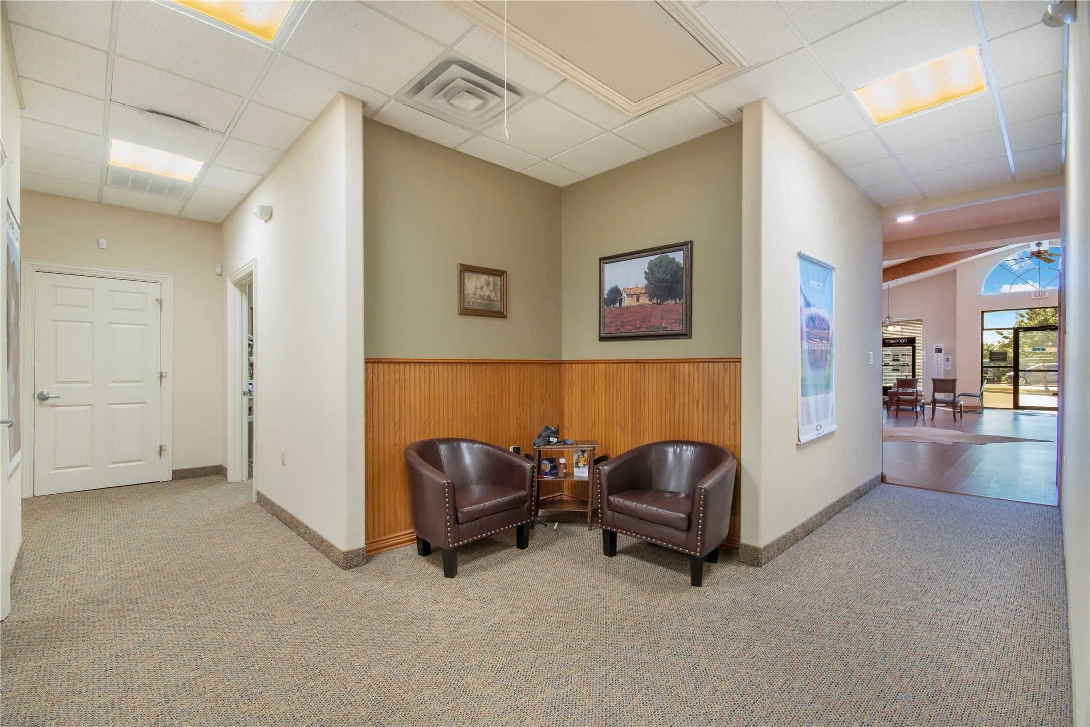 Hall featuring carpet flooring, wooden walls, a paneled ceiling, and wainscoting