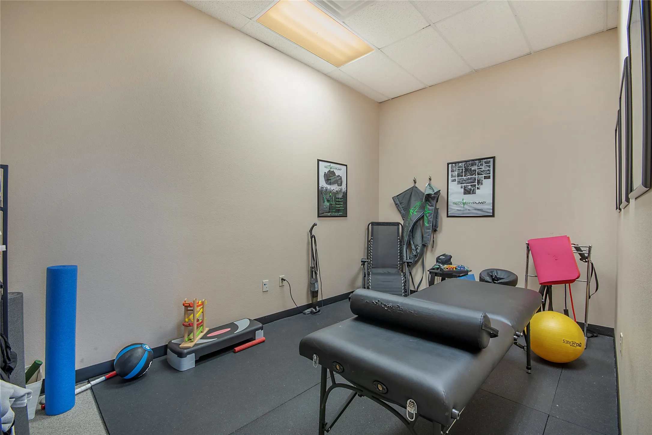 Workout area featuring a paneled ceiling and rubber floors