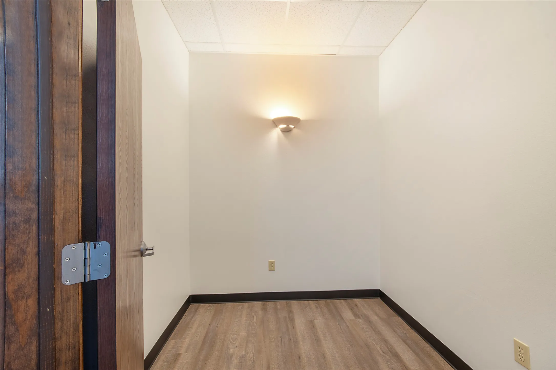Unfurnished room featuring a drop ceiling and light wood-style floors