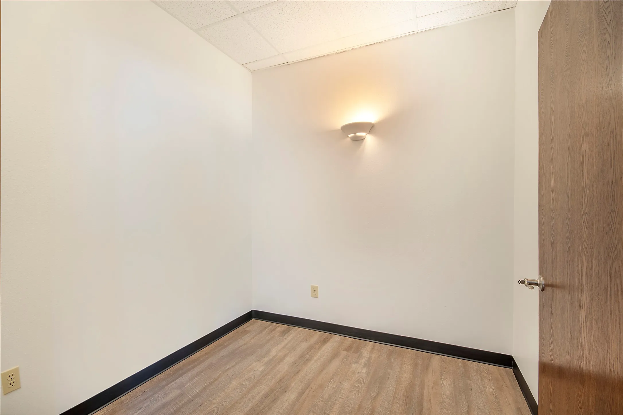 Unfurnished room with a drop ceiling and light wood-type flooring