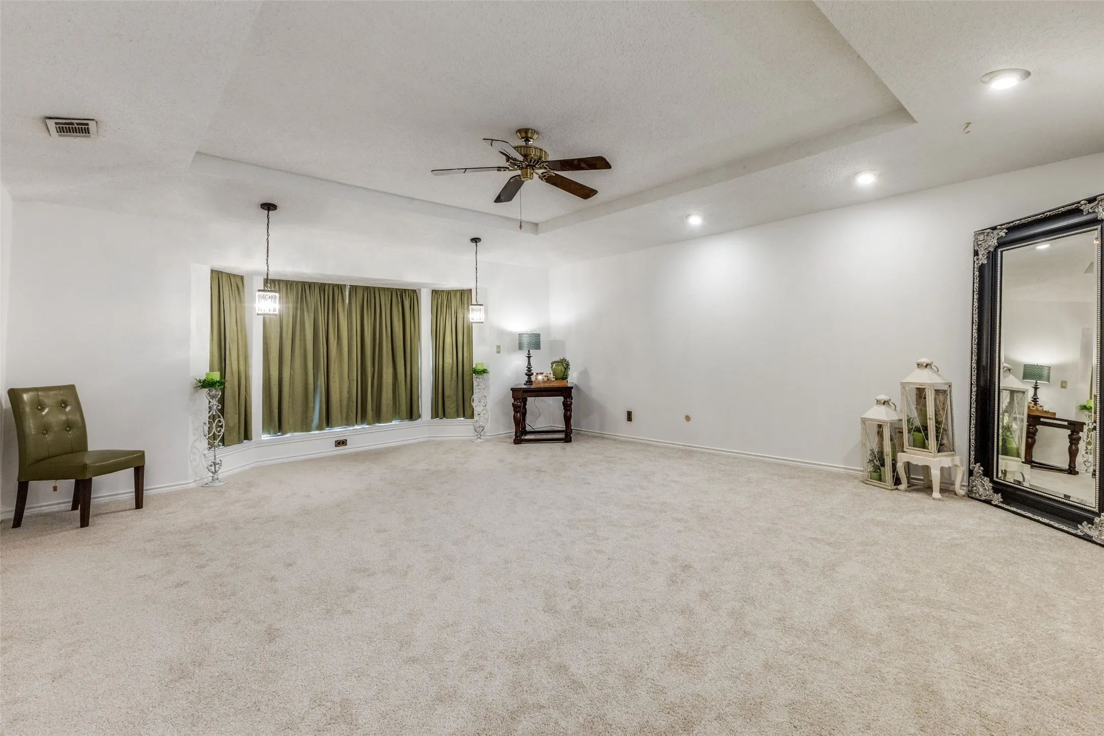 Primary bedroom with a tray ceiling, carpet flooring, a ceiling fan, recessed lighting, and a textured ceiling