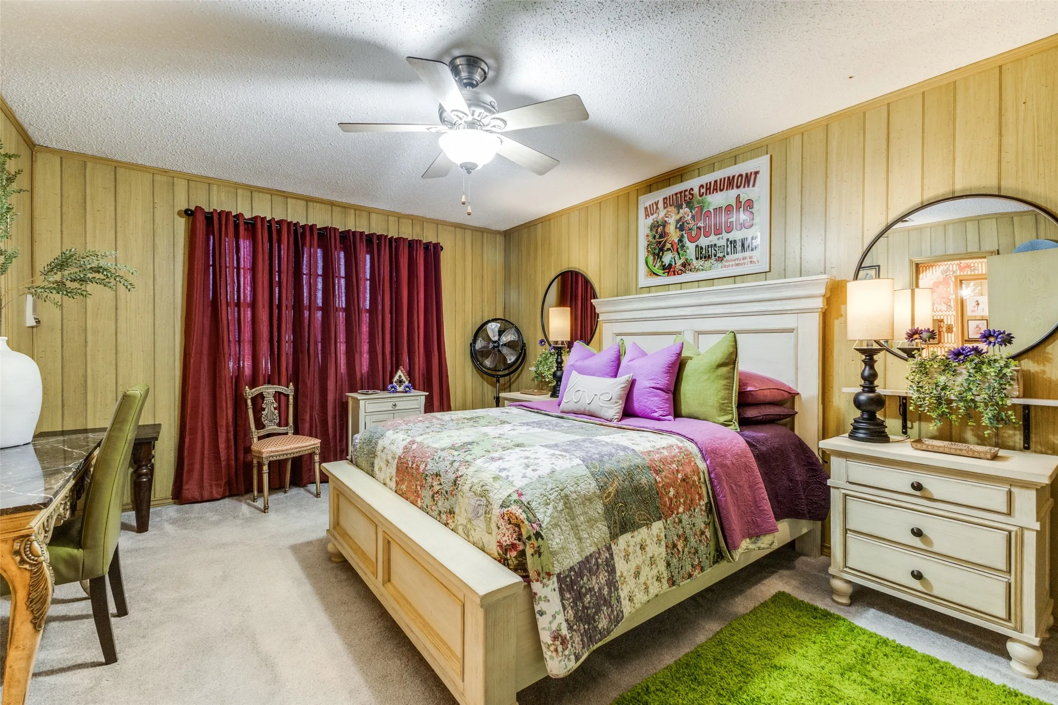 Carpeted bedroom with a textured ceiling, a ceiling fan, and wood walls