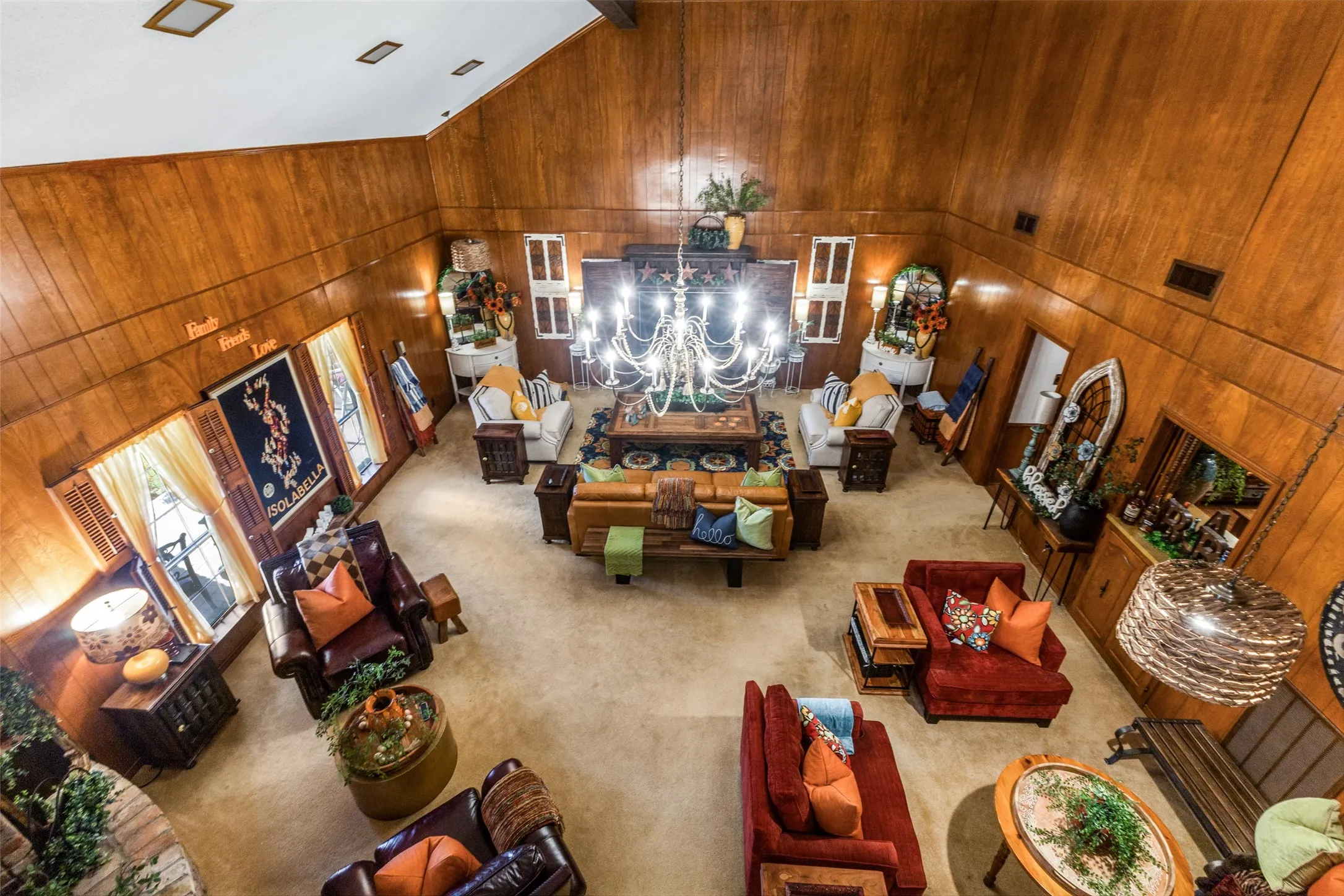 Carpeted living area with wooden walls, high vaulted ceiling, beam ceiling, and a chandelier