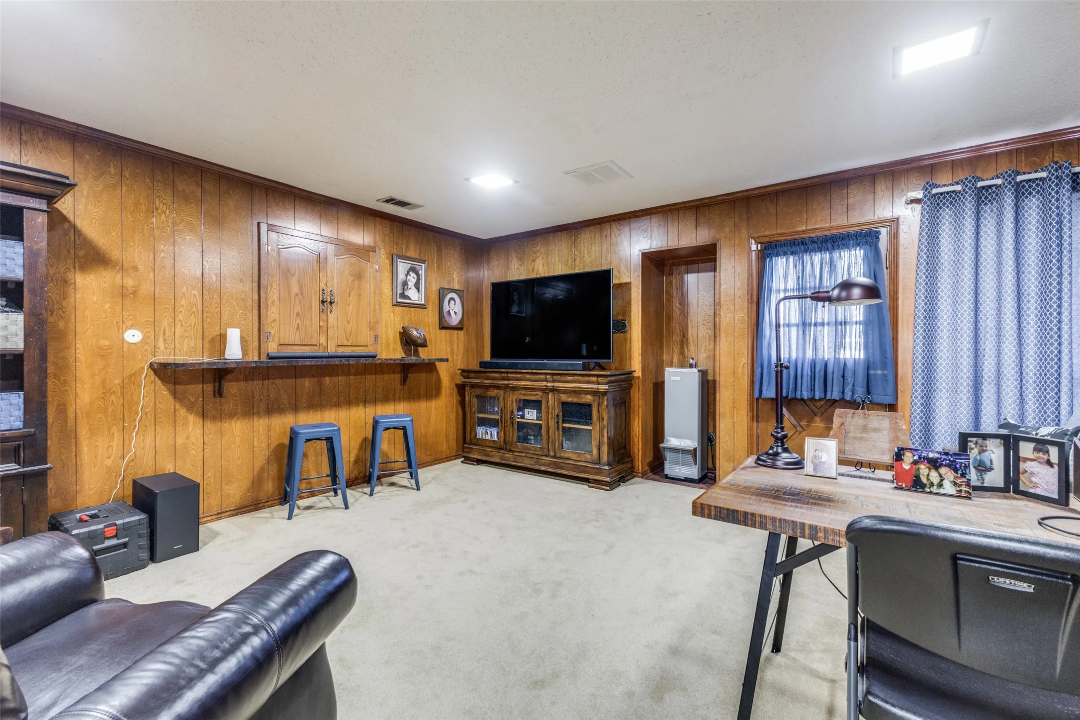 Bedroom featuring light carpet, wood walls, and ornamental molding
