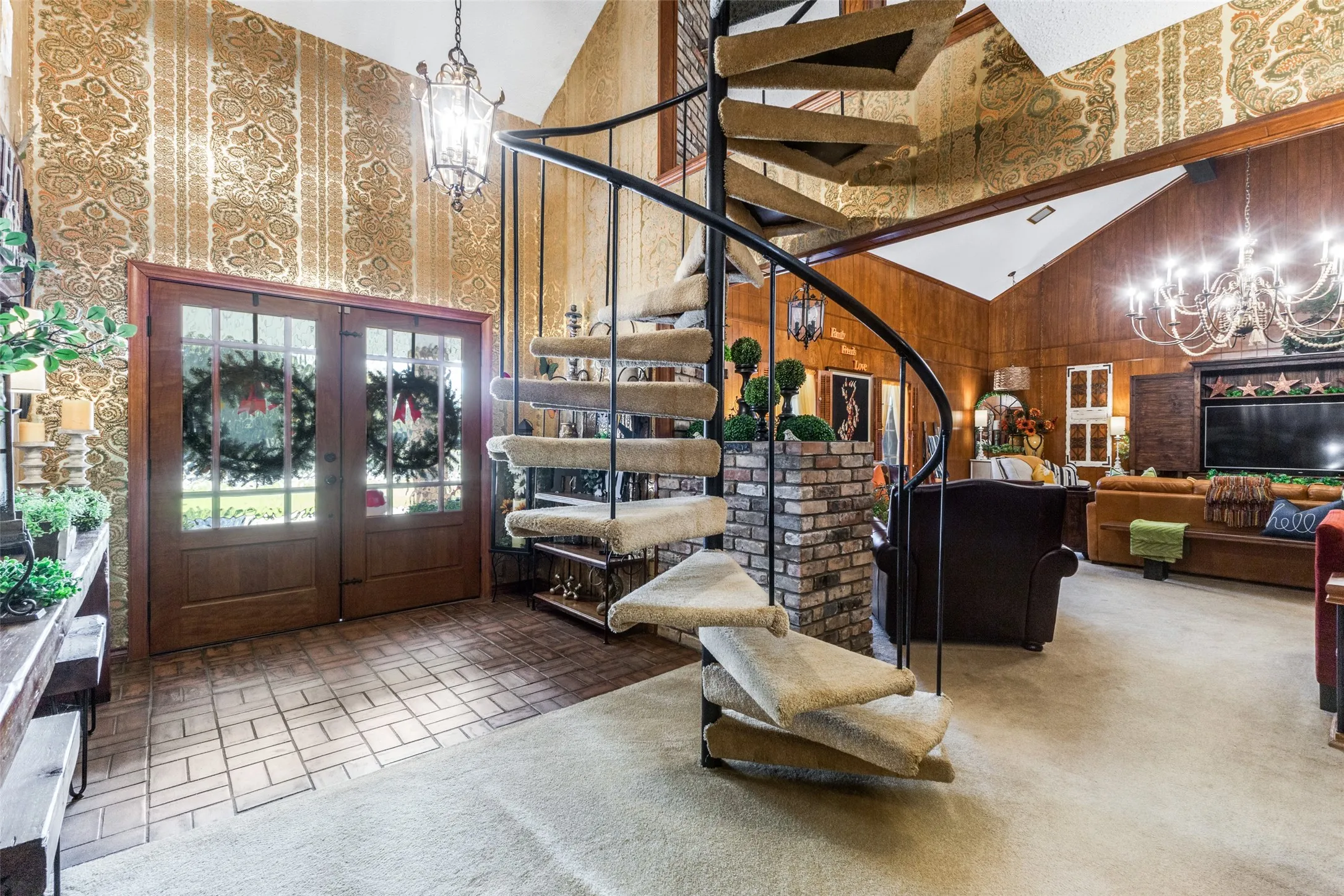Entryway with brick flooring, chandelier, high vaulted ceiling, french doors, and circular stairs to the loft area (game room) on the second floor.  All bedrooms are on the first level.