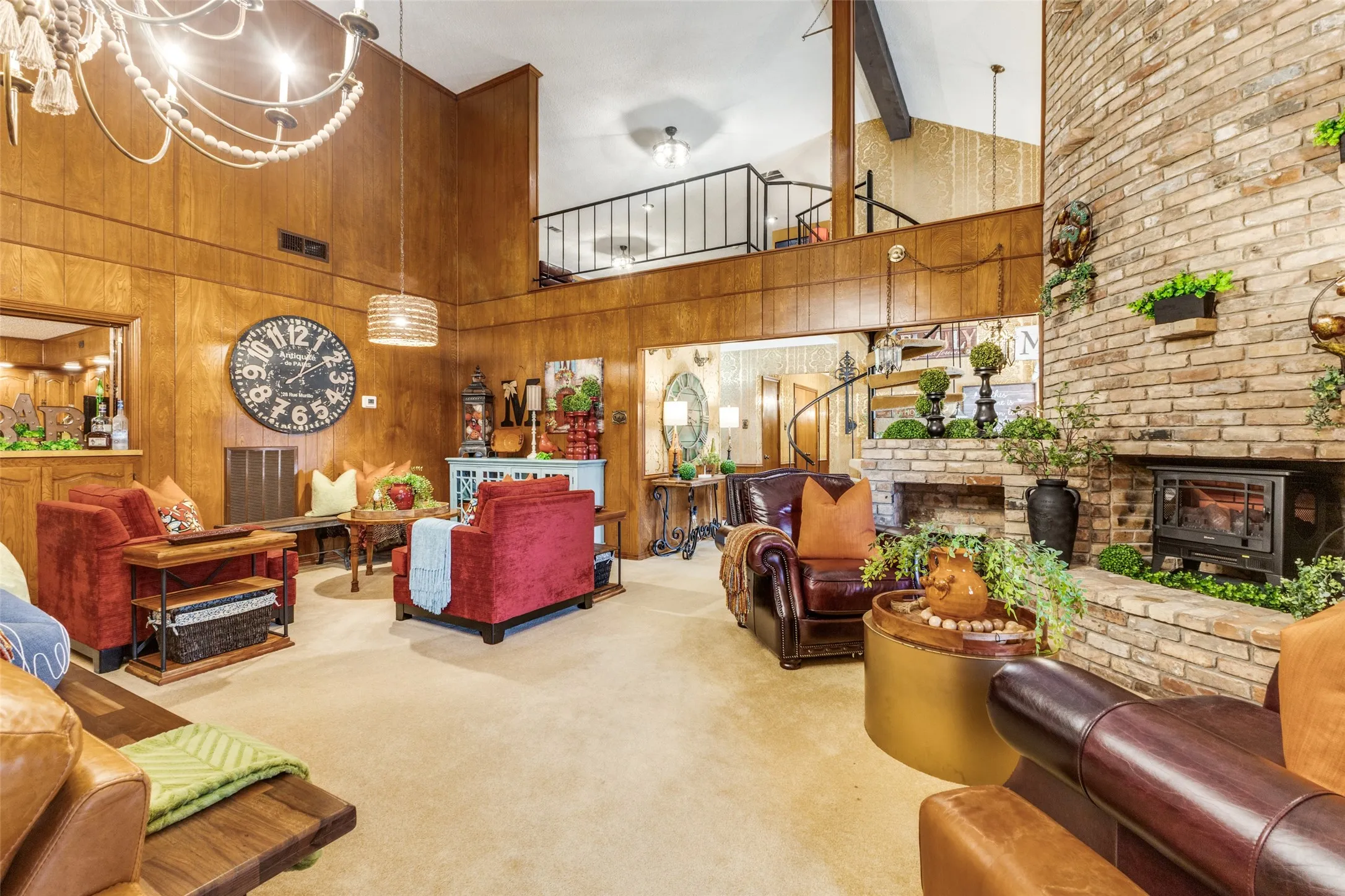 Carpeted living area featuring high vaulted ceiling, beamed ceiling, brick fireplace and hearth, and a ornate lighting.