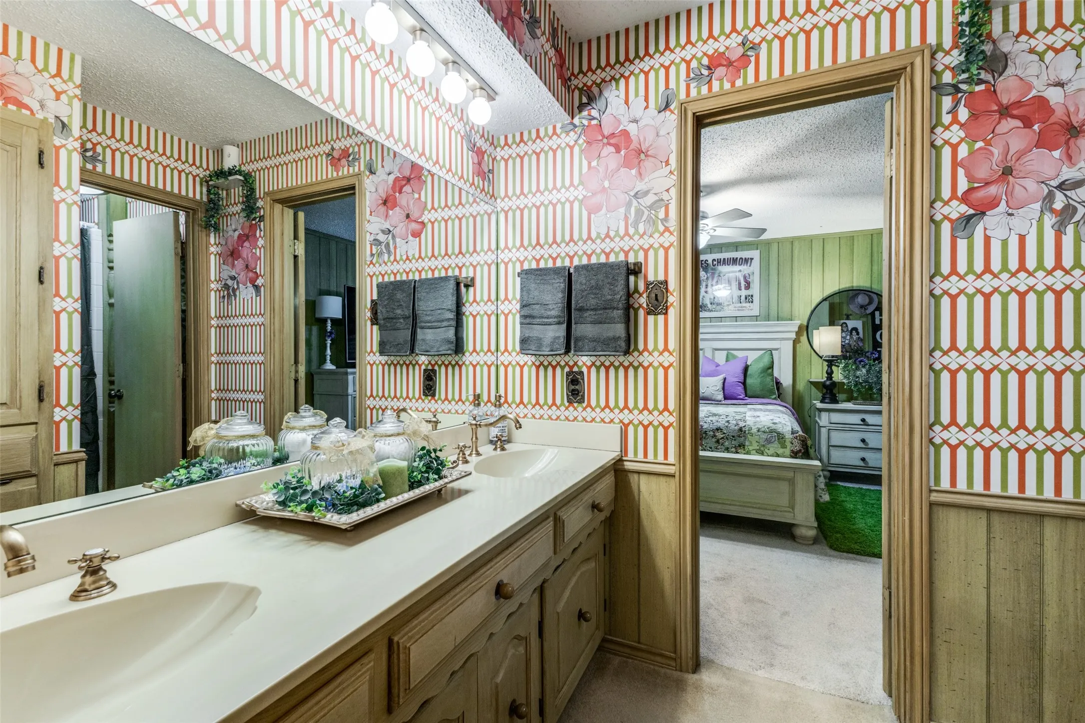 Bathroom with ensuite bath, double vanity, light colored carpet, and wallpapered walls