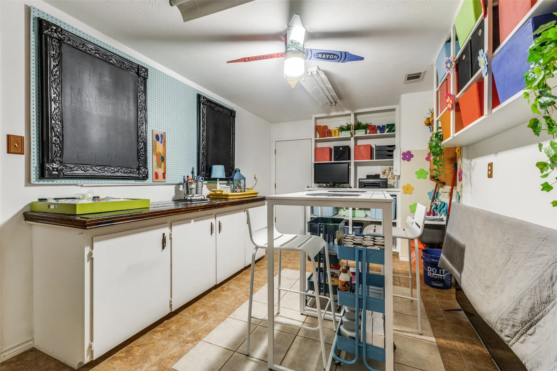 White cabinetry, light tile patterned flooring, dark countertops, and ceiling fan.  Lots of space for your crafts!  Or use it as an office