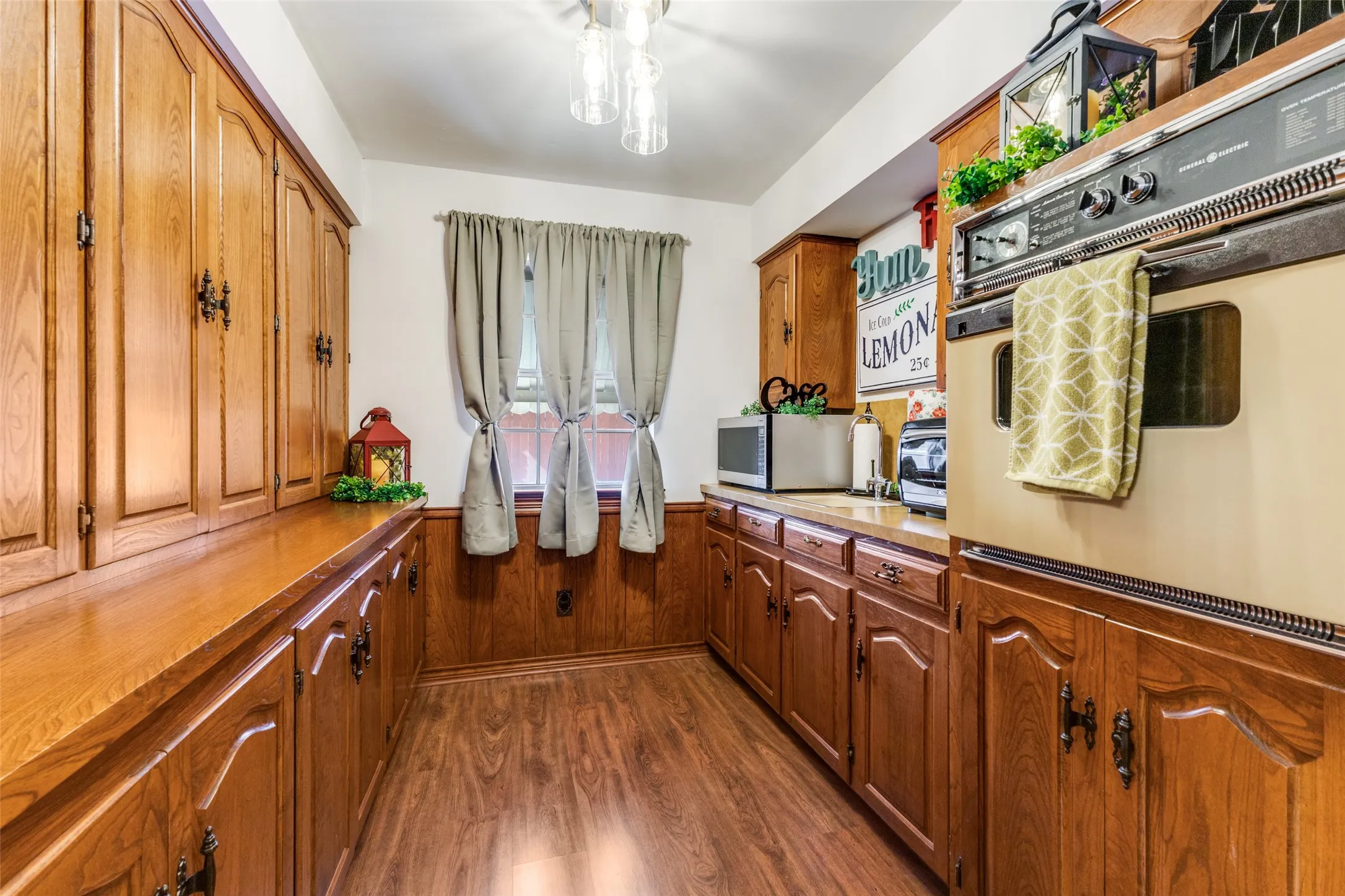 Kitchen featuring huge walk-in pantry with wainscoted wall, dark wood finished floors and abundant cabinets.