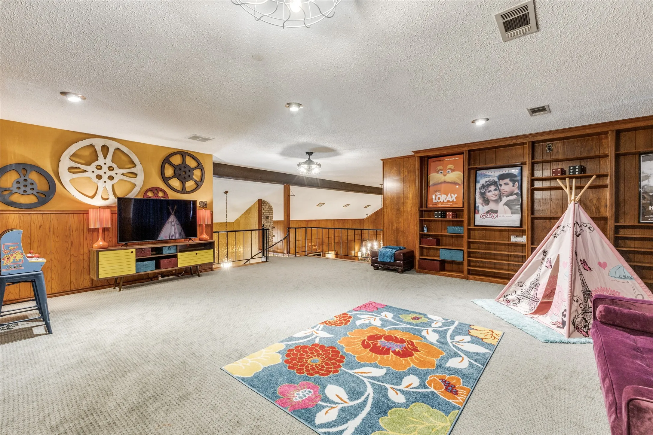 Recreation room featuring wooden walls, carpet, and a textured ceiling