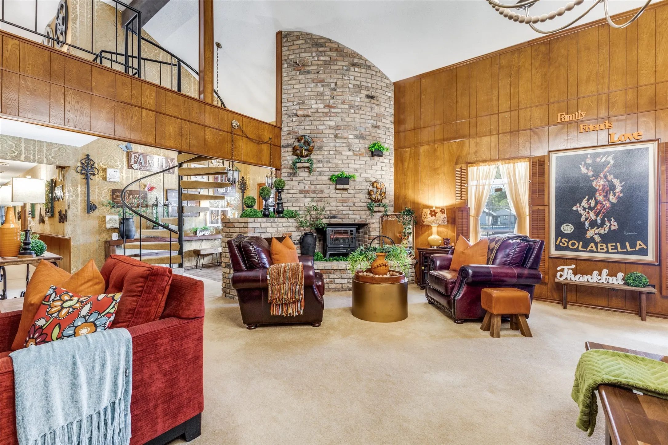 Great room featuring wood-paneled walls, a stunning brick fireplace, high vaulted ceiling and plush carpet flooring.  Lots of seating areas in this great room.